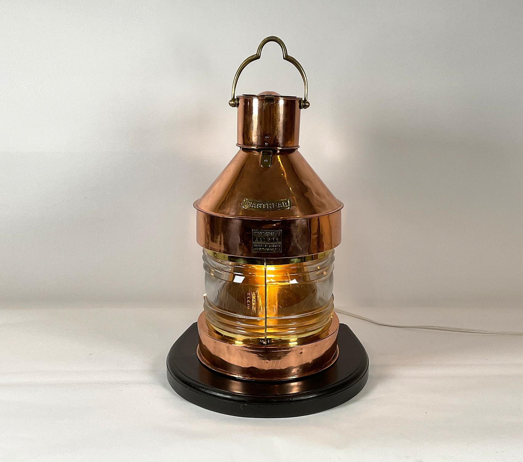 Copper ship’s masthead lantern by English maker “Meteorite”. Brass maker’s badge with serial number A11235. Also fitted with an embossed brass “masthead” badge. Mounted to a thick wood base and wired with an electric socket. Meticulously polished