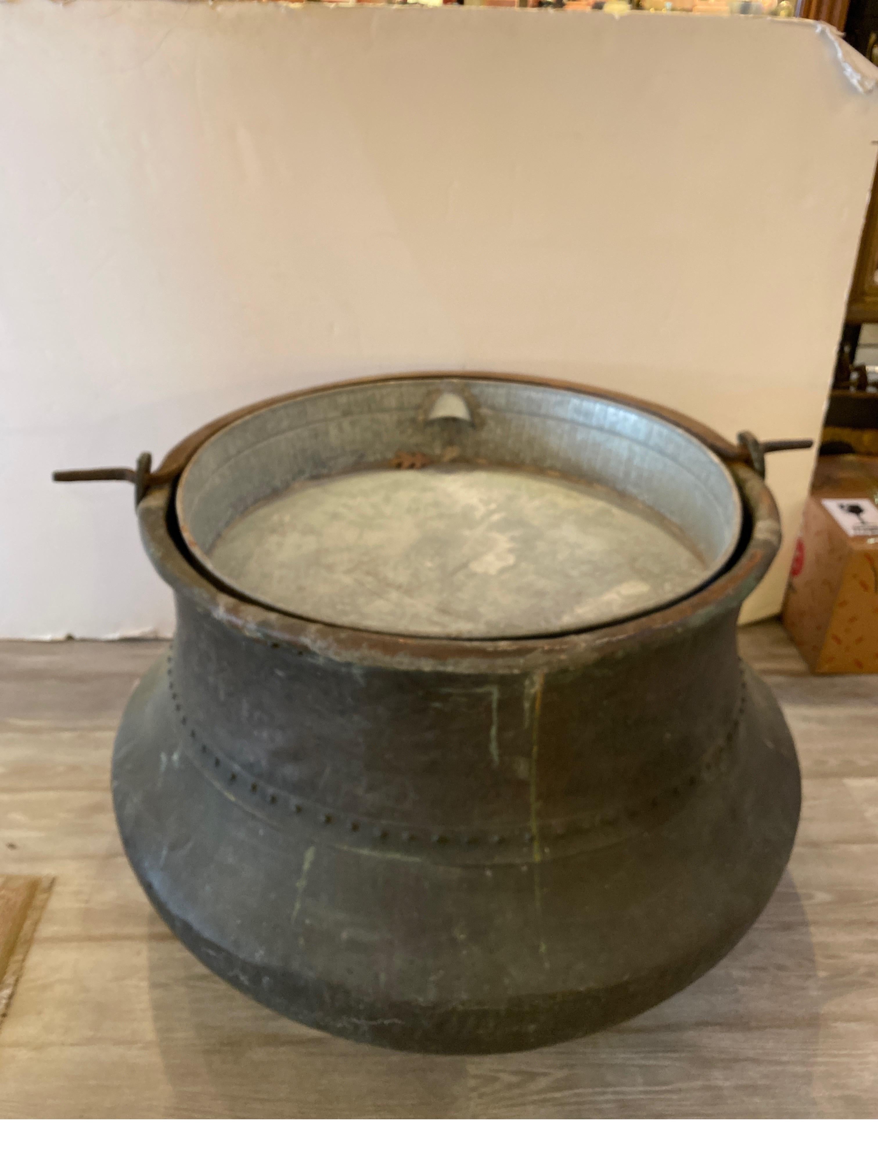 A very large copper cauldron with later added galvanized liner with welded steel support. The naturally aged copper surface with with hand forged iron handle. The pot is initialed R.C.P. and dated 1836. Hand made with later drilled holes at teh