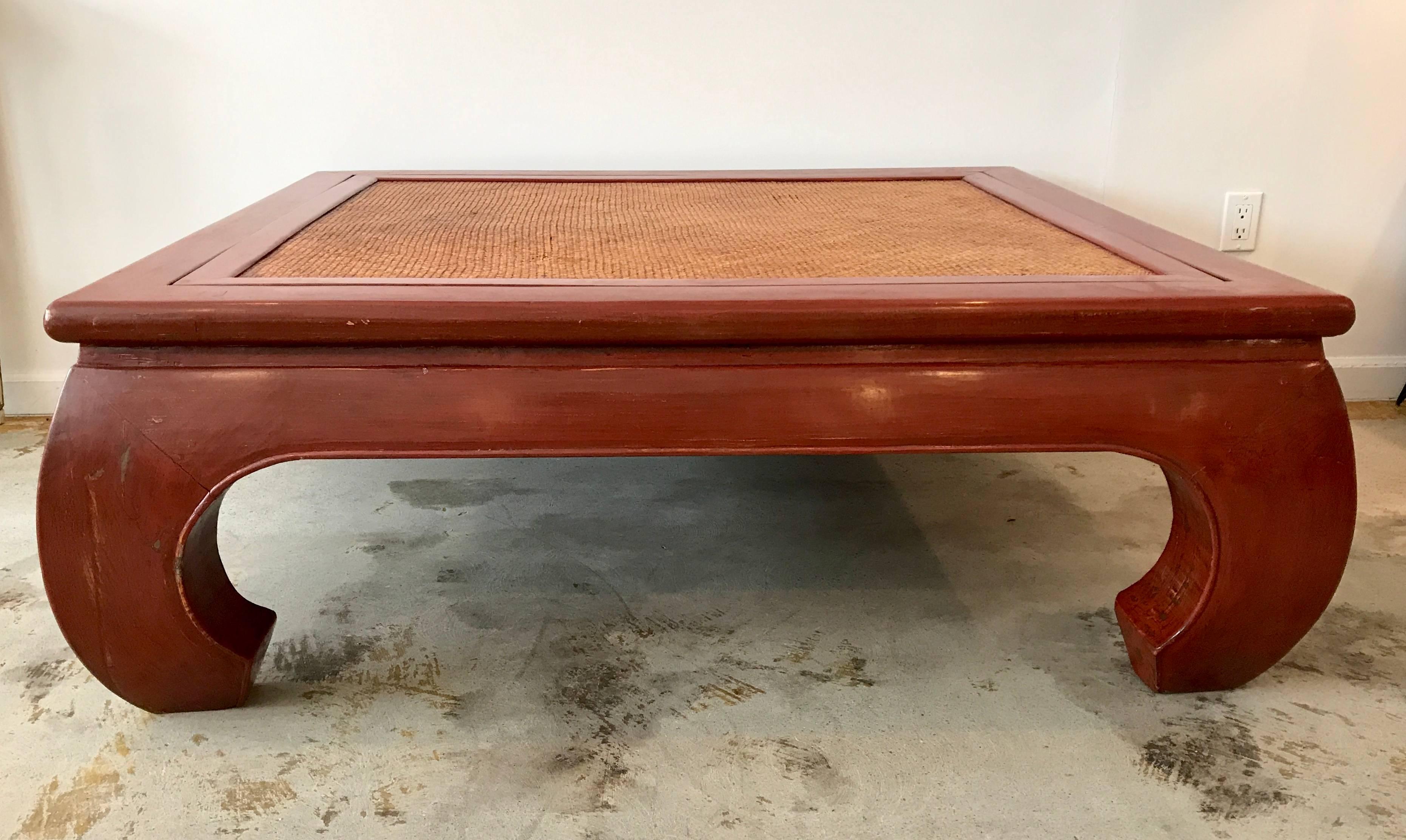 Massive, beautiful Chinese chow leg coffee table painted a vibrant coral red, cane top that is reversible.