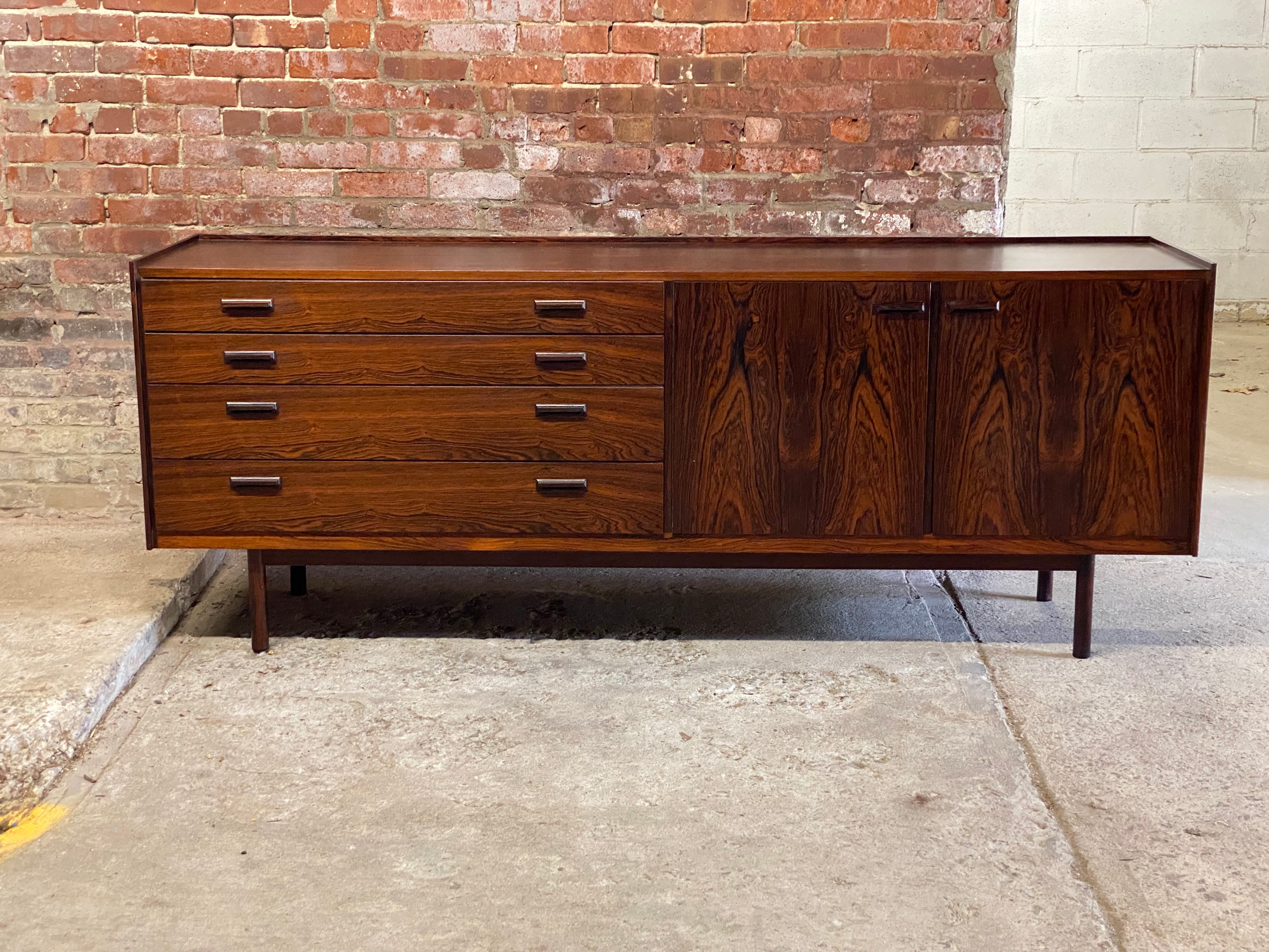 Tremendous figured rosewood Danish sideboard. Circa 1960-70. Exceptional quality. Danish Control tag in one drawer. Featuring four drawers and two doors with adjustable height shelves, sliding vanity tray, solid rosewood front interior drawers and