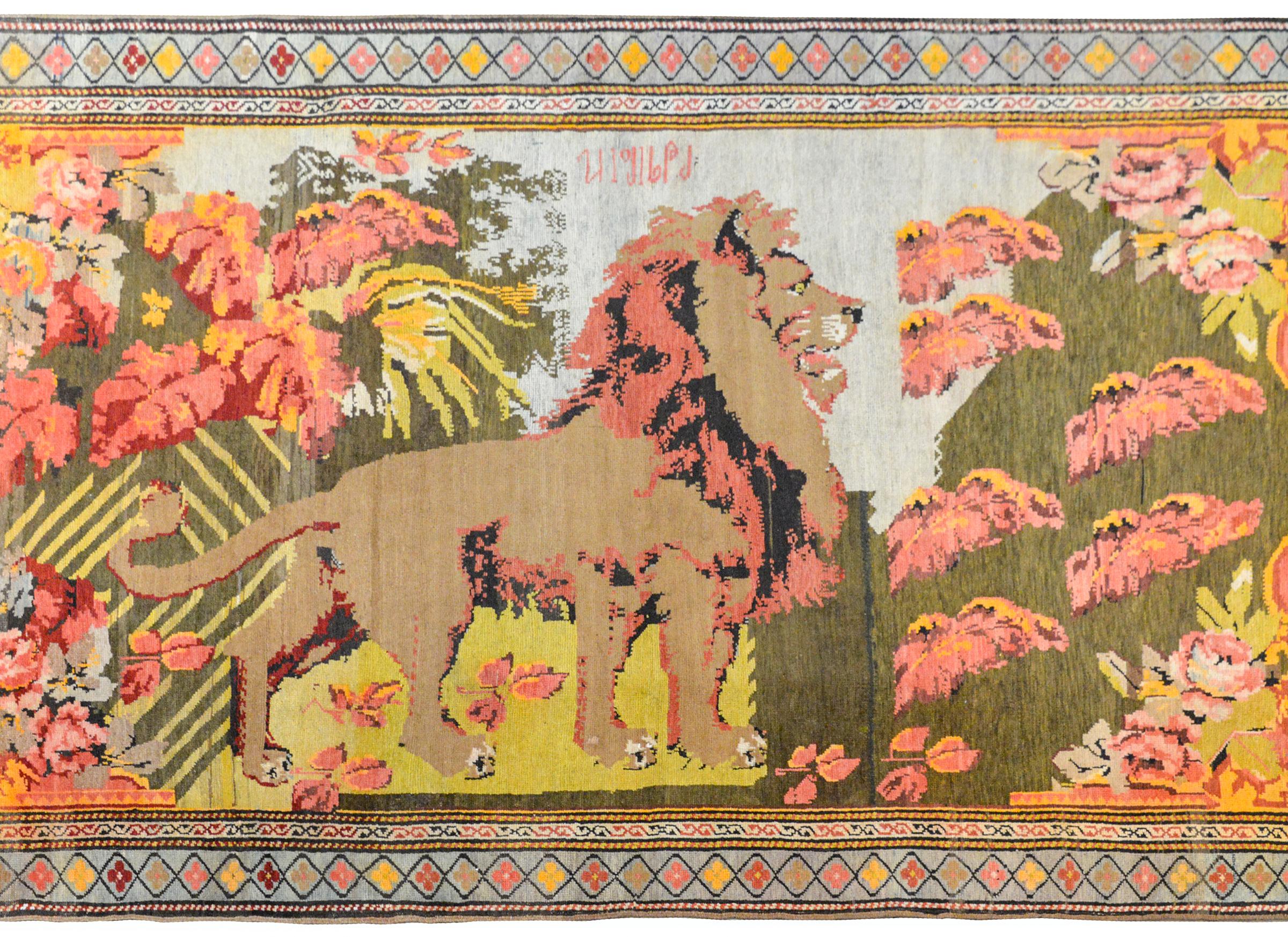 A fantastic massive early 20th century Caucasian pictorial Karabagh rug depicting a large lion, fully rendered, and standing amidst a jungle of tropical plants and trees and large cabbage roses in each corner, all woven in crimson, pink, gold,