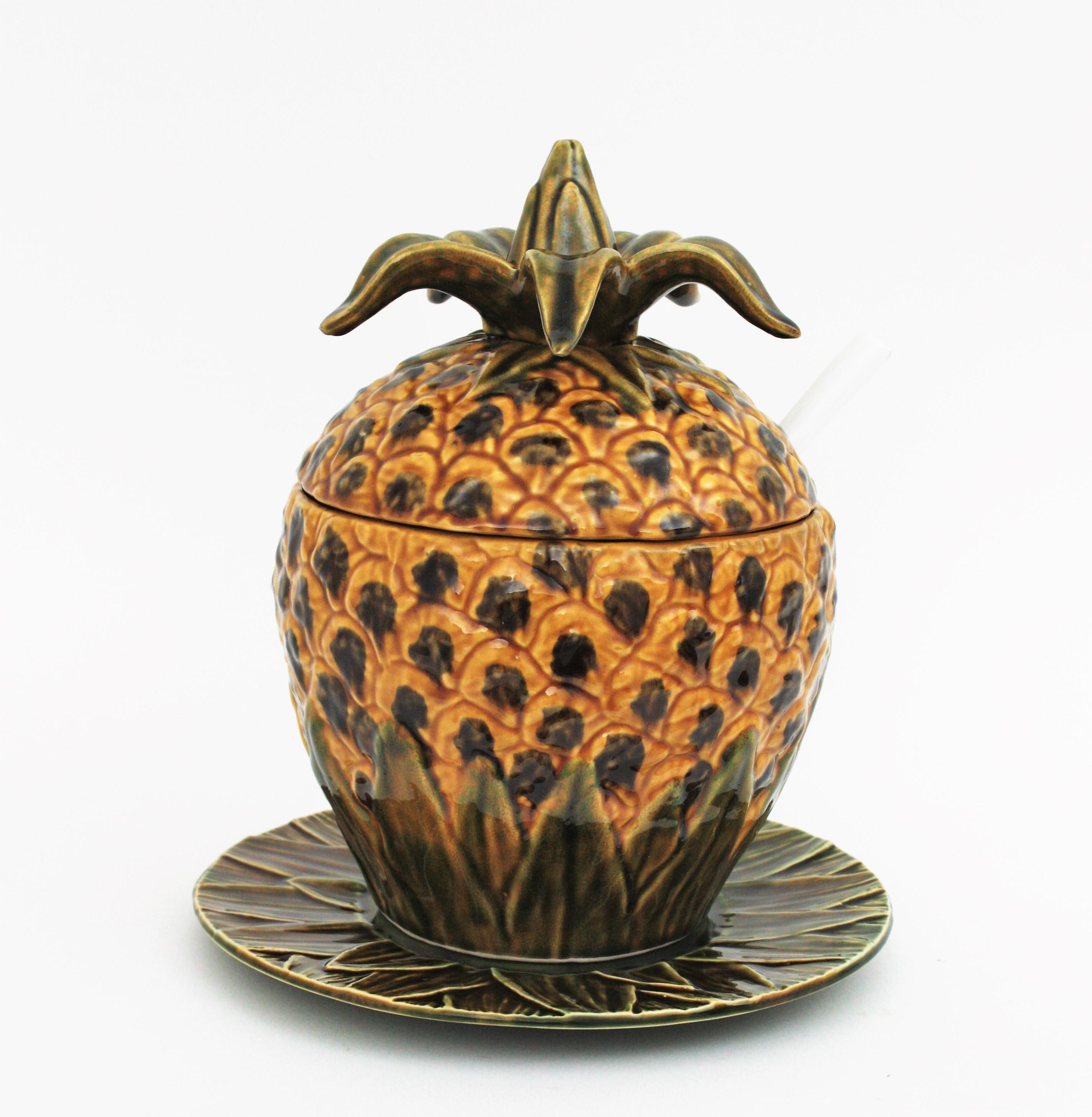 Ananasterrine mit Teller und Schöpfkelle; Majolika, glasierte Keramik. Portugal, 1960er Jahre
Diese große Terrine hat ein sehr realistisches Ananas-Design. Eine Servierplatte mit Blattmotiv und eine Schöpfkelle vervollständigen das Set. 
Dieses
