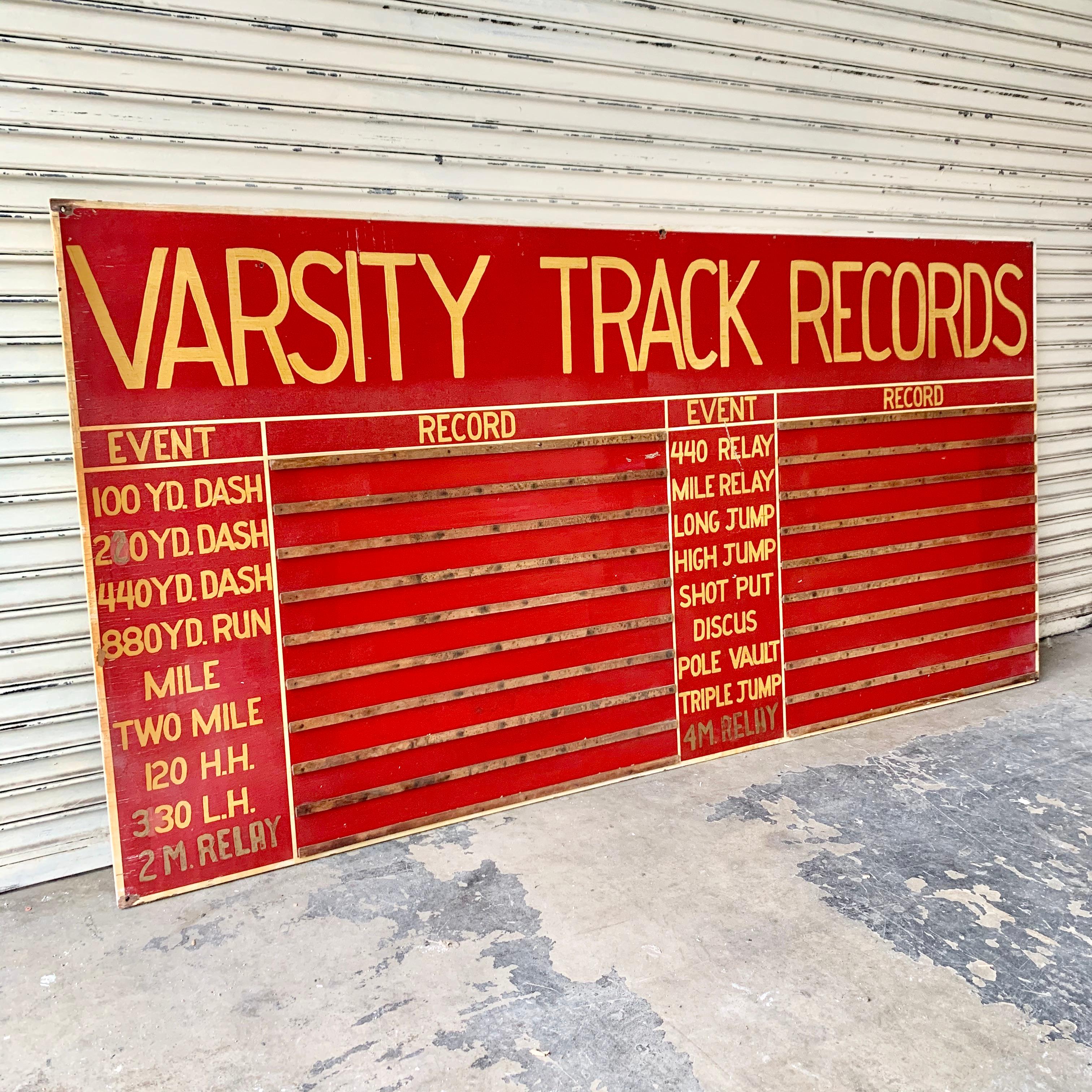 Varsity track and field sign from the early 1970s. Hand painted red sign with yellow lettering. Horizontal wood slates to hold name cards of record holders. Measures: 8 feet wide, 4 feet tall. Great coloring and presence. Good vintage
