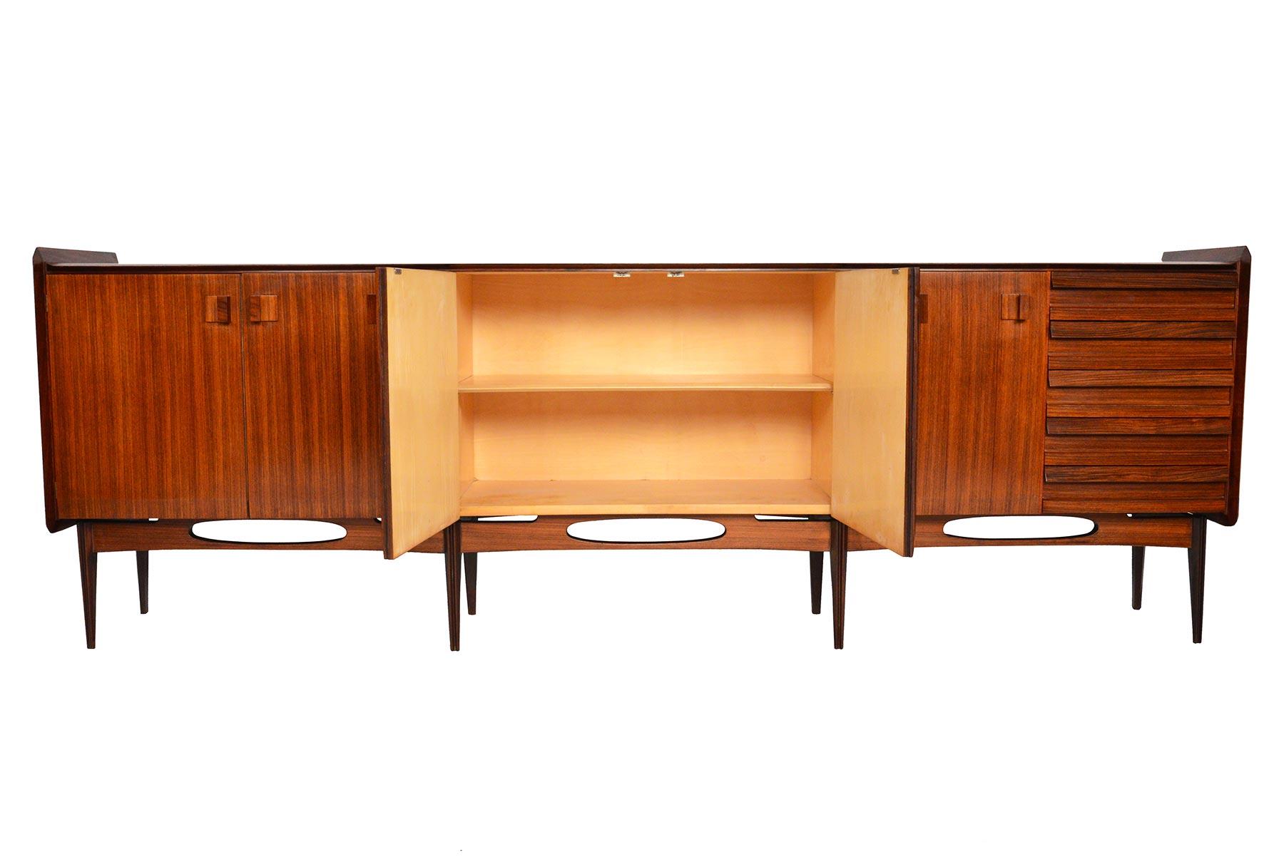 This astounding Italian Mid-Century Modern credenza from Artigiani Canturini del Mobile is a masterfully crafted rosewood showpiece. Beautiful angled banding and side edges crown the top of this sideboard. Comprised of three bays and standing on