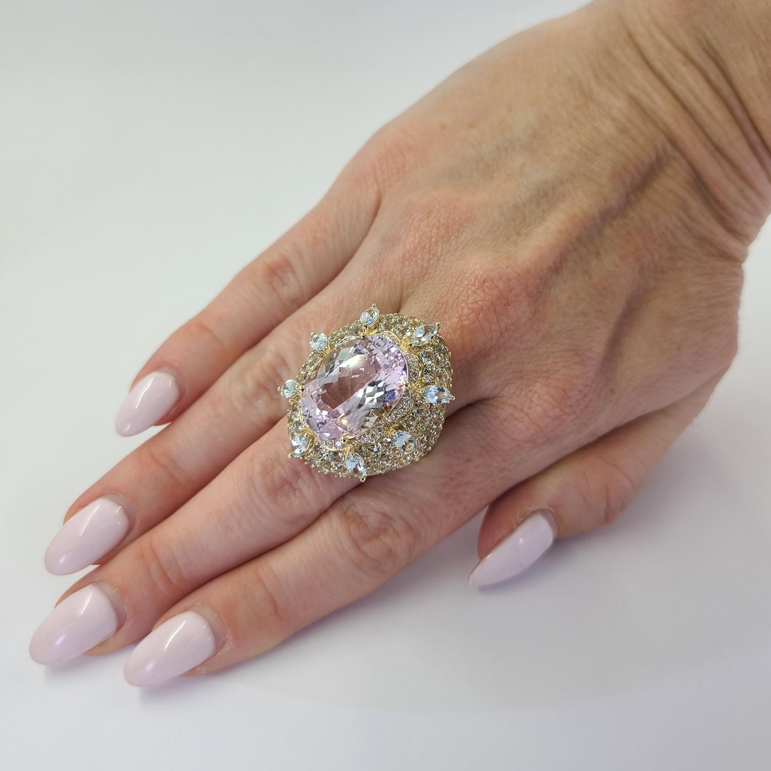 Exceptional 14 Karat Yellow Gold Cocktail Ring Featuring A Large 18 Carat Oval Cut Kunzite Accented By 162 Aquamarines Totaling Approximately 10 Carats, and 24 Round Brilliant Cut Diamonds of VS Clarity and G/H Color Totaling 0.12 Carats. Current