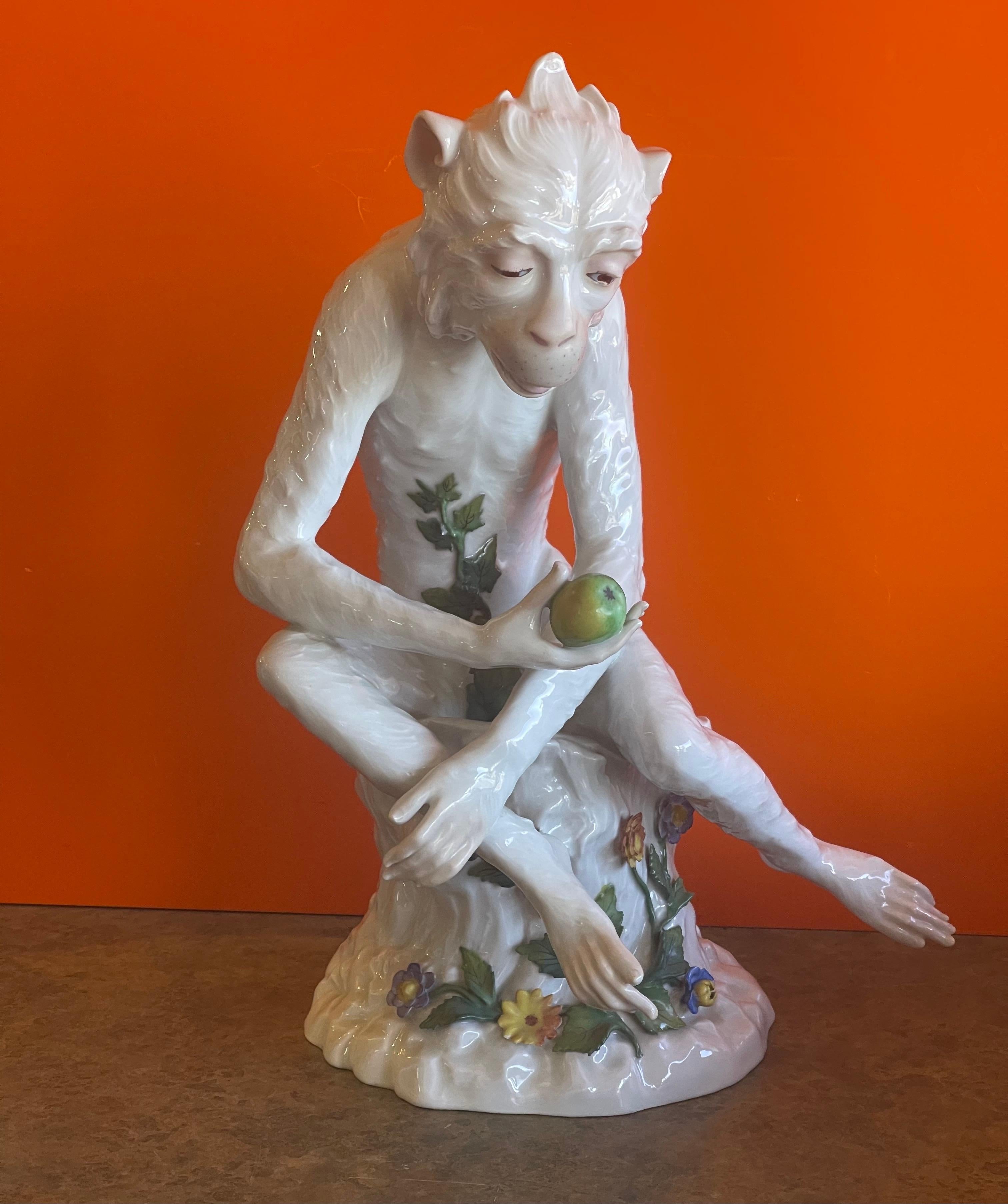 Large antique porcelain monkey sculpture based on the design by Johann Gottlieb Kirchner for Dresden Porcelain, circa 1900. The piece depicts a monkey sitting hunched over on a tree stump, holding an apple in his hand, in a naturalistic form; the