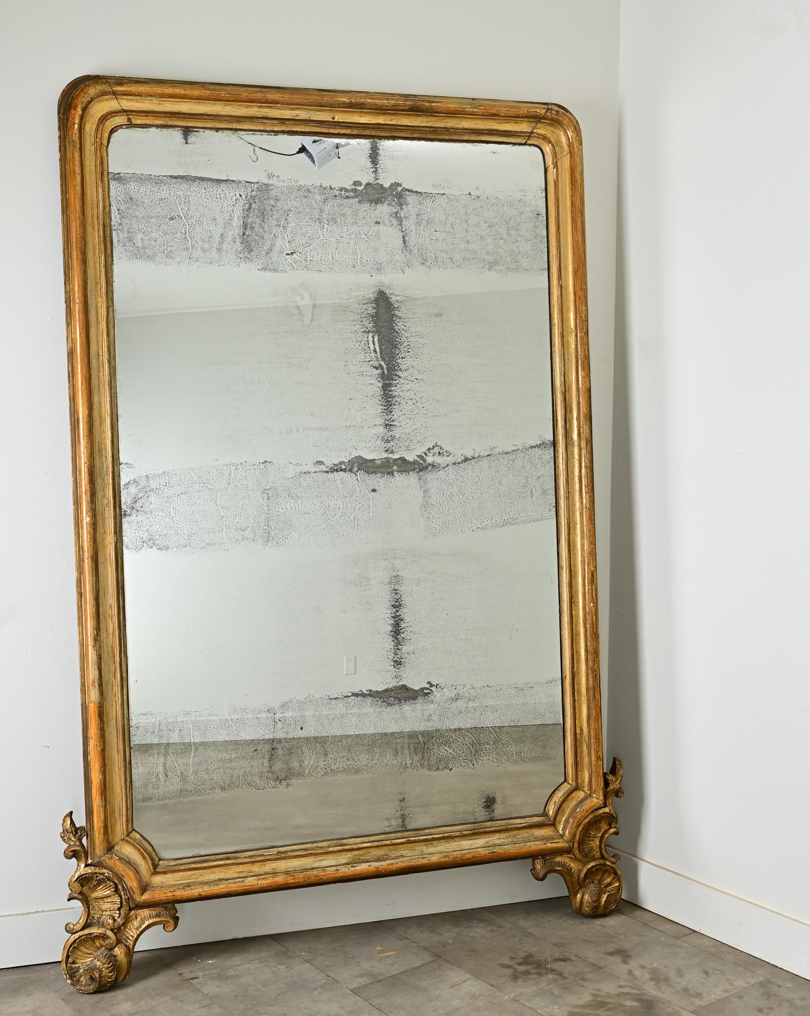 Incantevole specchio in legno dorato Louis Philippe di dimensioni senza precedenti. La lastra a specchio originale presenta foxing e cristallizzazione in striature sfumate che conferiscono una qualità pittorica a questo pezzo già unico. I pesanti
