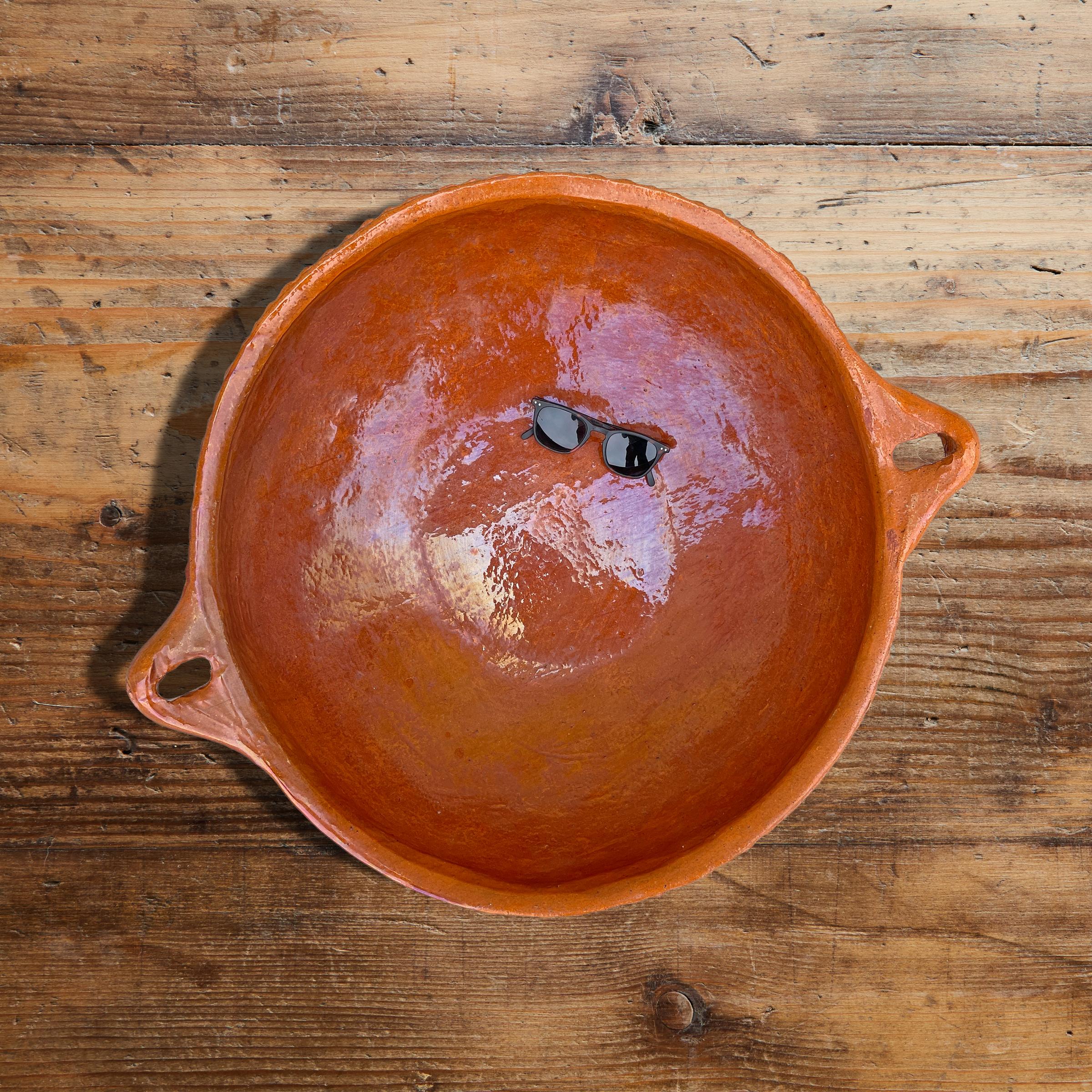 A massive vintage Mexican terracotta bowl with two handles, a ruffled lip, and a glazed interior with an unglazed exterior. Perfect for holding fruits and vegetables on your kitchen island, or ask us about having a custom mount made so it can be