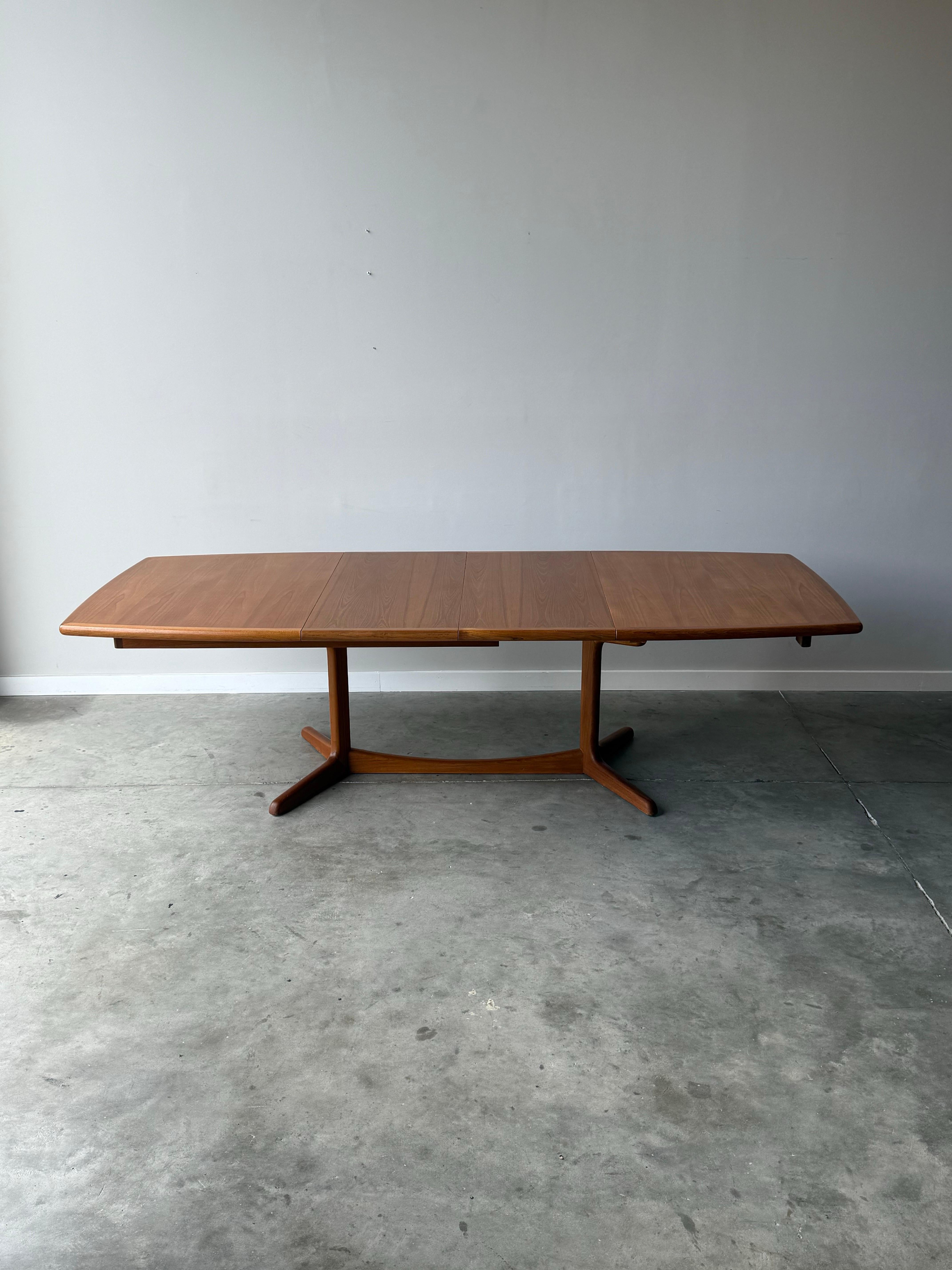 Massive table de salle à manger danoise du milieu du siècle. Fabriqué en bois de teck avec un magnifique grain de bois. De forme rectangulaire, ses coins arrondis lui confèrent une certaine douceur. Cette pièce est équipée de deux vantaux
