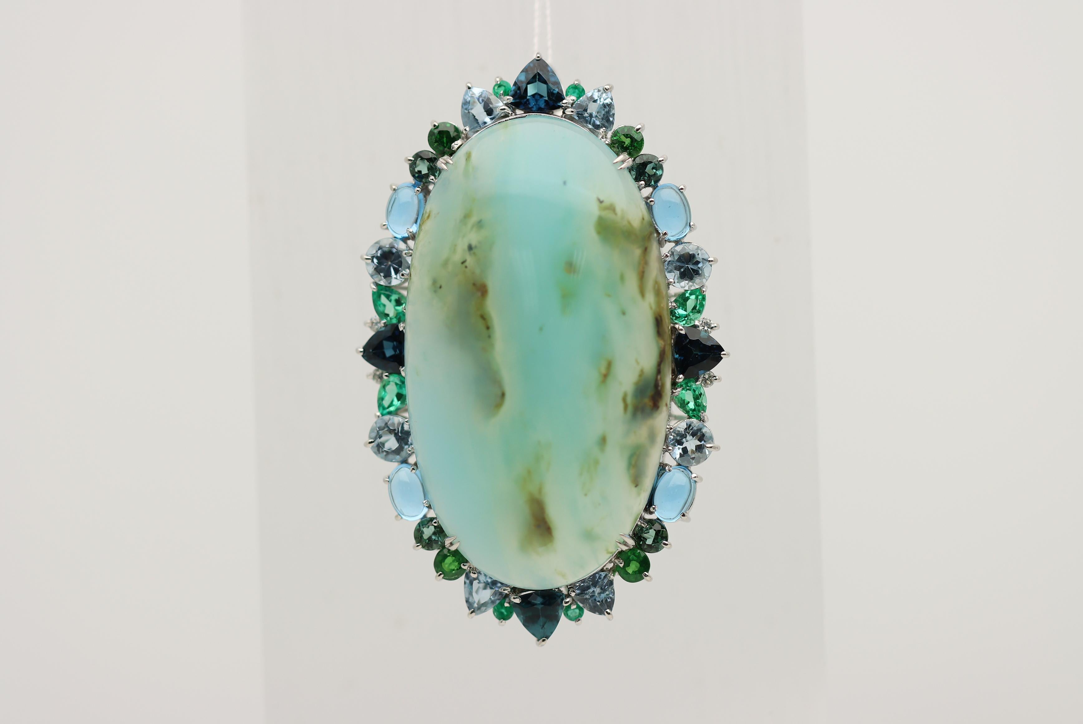 Feel empowered while wearing this regal and impressive brooch featuring a 58.81 carat natural blue opal! It has a smooth even polish over its dome along with traces of the host rock it grew with giving the stone character. It is surrounded by a