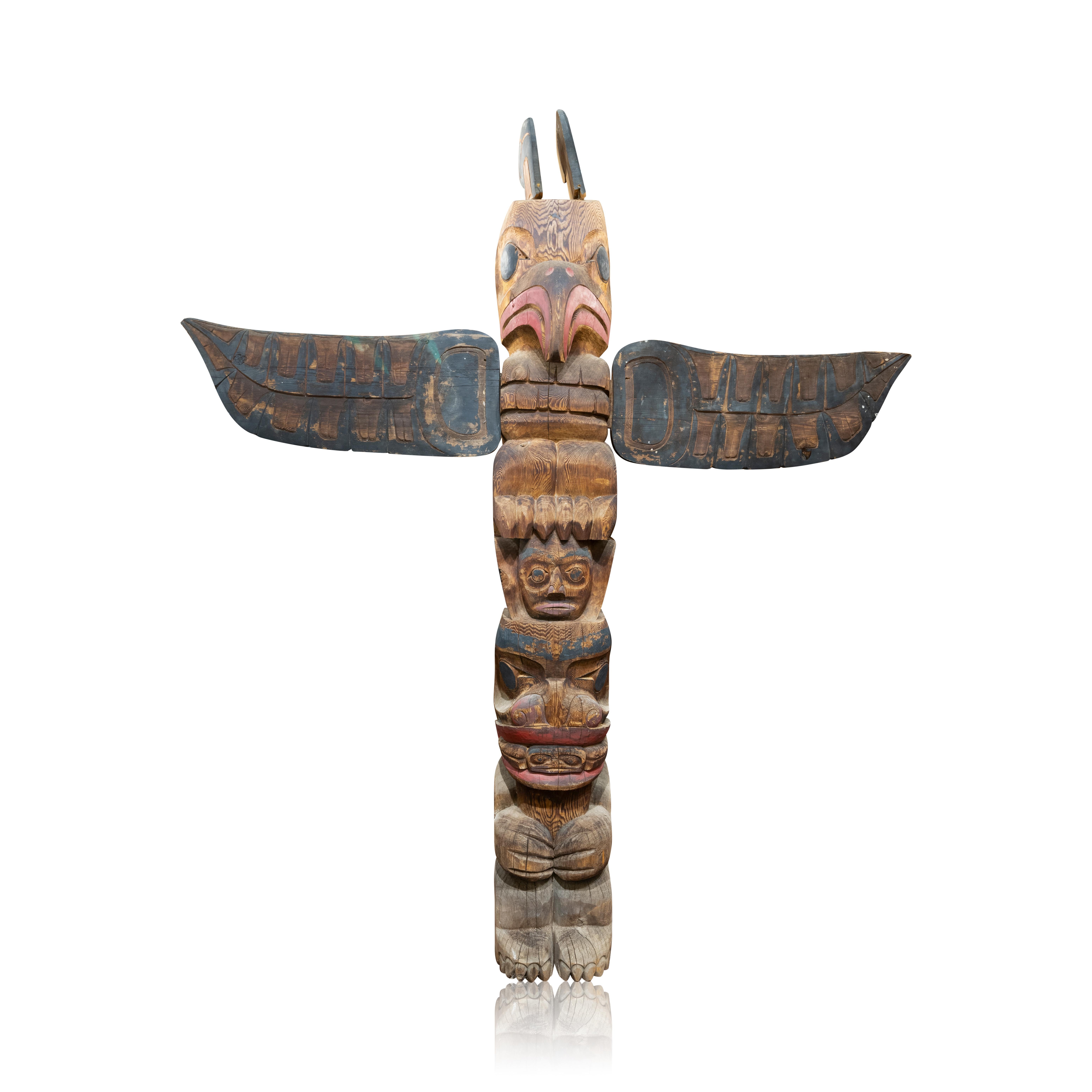 Matched pair of Salish Native American totem poles. Both identical. Carved as a thunderbird with spread rings separately carved and attached perched on the head of a human over a seated bear figure with a frog emerging from the ursine mouth.