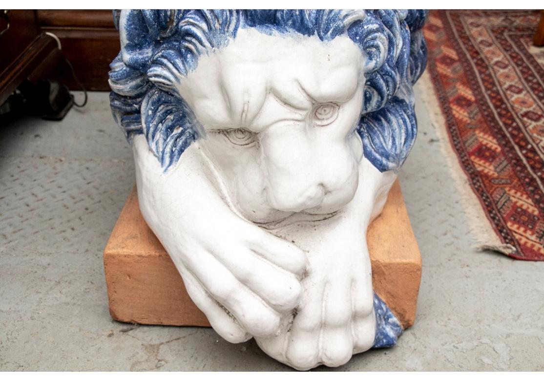 A pair of powerfully modeled recumbent male lions in white glaze with blue fur details. Mounted on terra-cotta bases.
Measures: Length 54