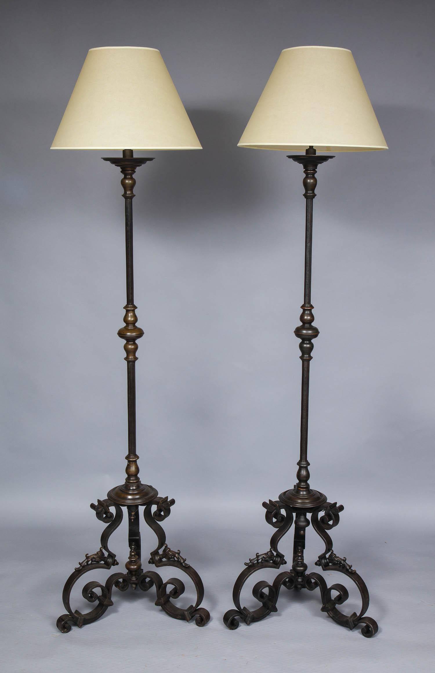 Very fine quality pair of bronze and wrought iron torchere floor lamps having richly patinated bronze bobeches, collars and bands, the octagonal iron shafts in hand hammered iron, standing on scrolled iron bases with additional bronze decorations