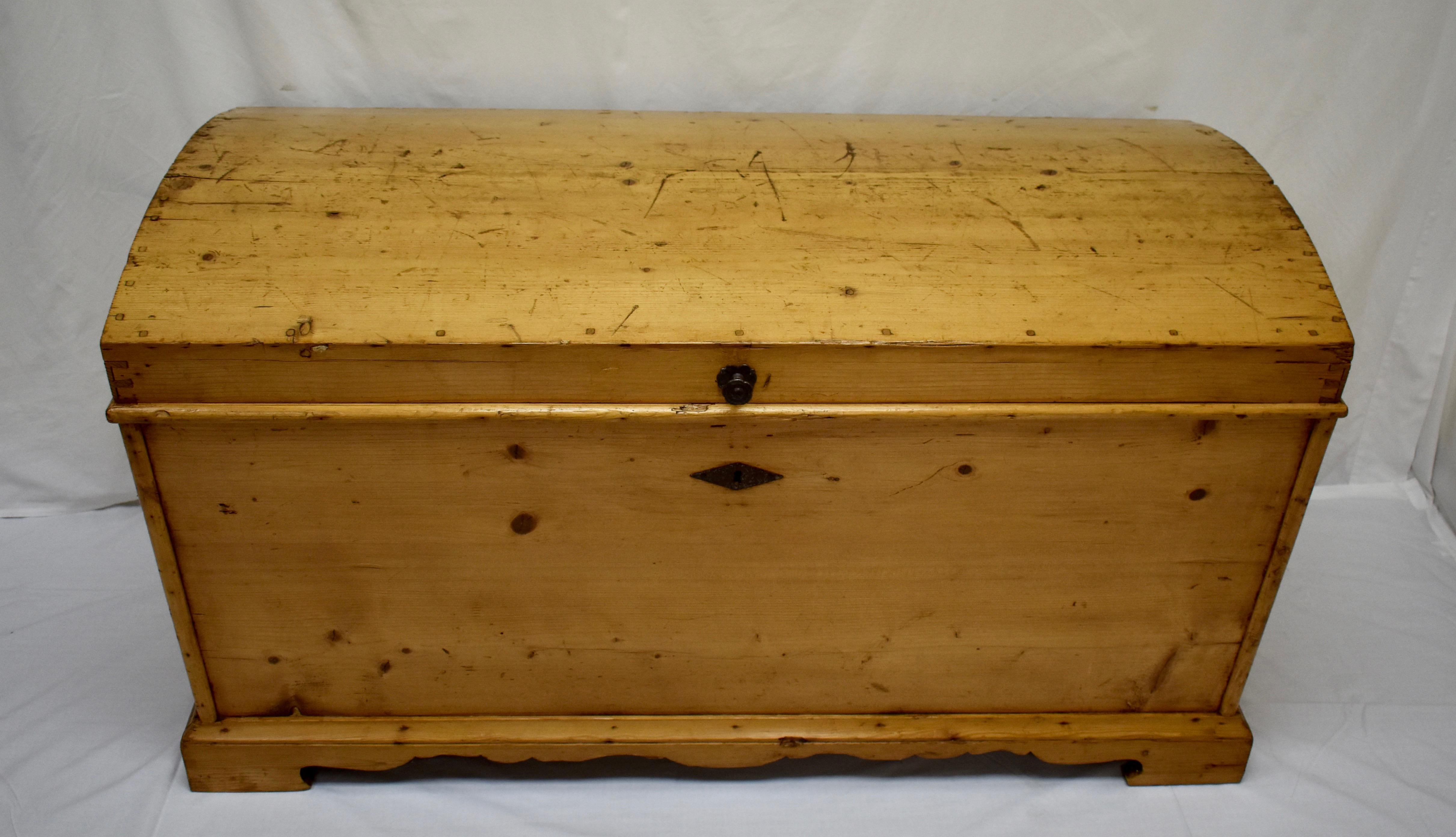 This outstanding stately pine dome-top trunk is one of the largest and nicest we have seen in a long time. It is of entirely handcut dovetailed and pegged construction. The three board top is fitted so well that it looks like a single board. The