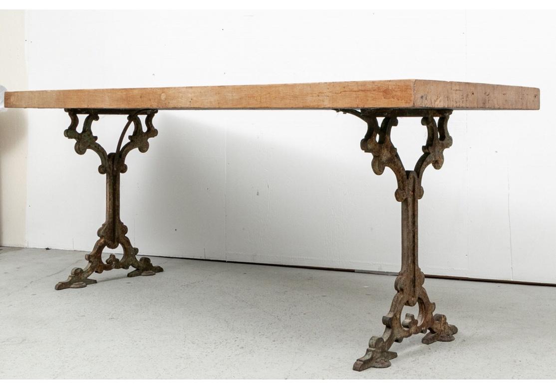 A plank constructed pine tabletop mounted on a pair of decorative iron supports. The decorative 19th c. cast iron supports with open scrolled tops and bases with extended flat feet. In old green paint. 

L. 84
