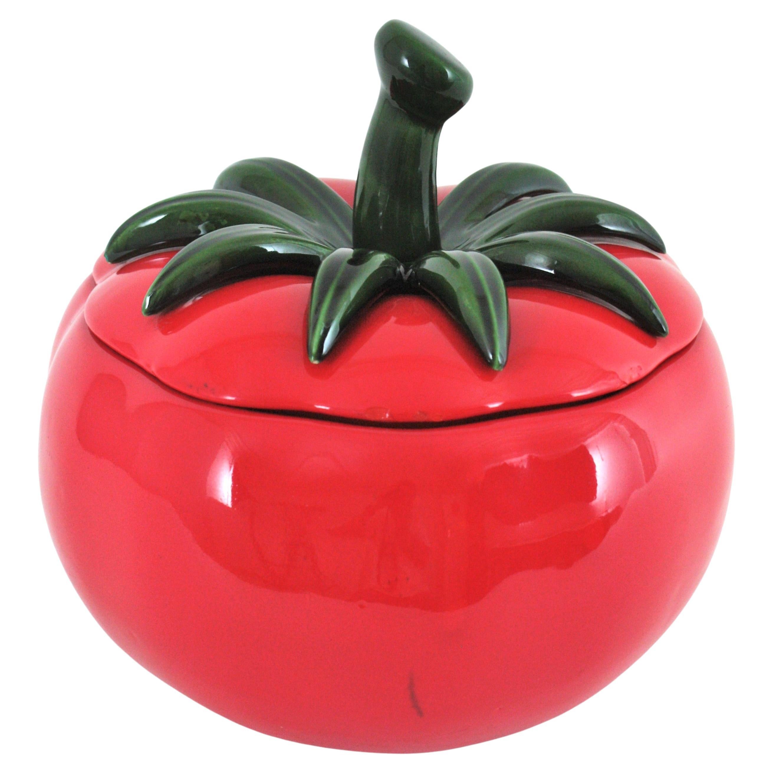 Eye-catching red Majolica ceramic tomato shaped tureen, Spain, 1960s.
This huge tureen has a very realistic design with green leaves on the lid. The vibrant red color is eye-catching.
This highly decorative serving piece will be a nice addition to