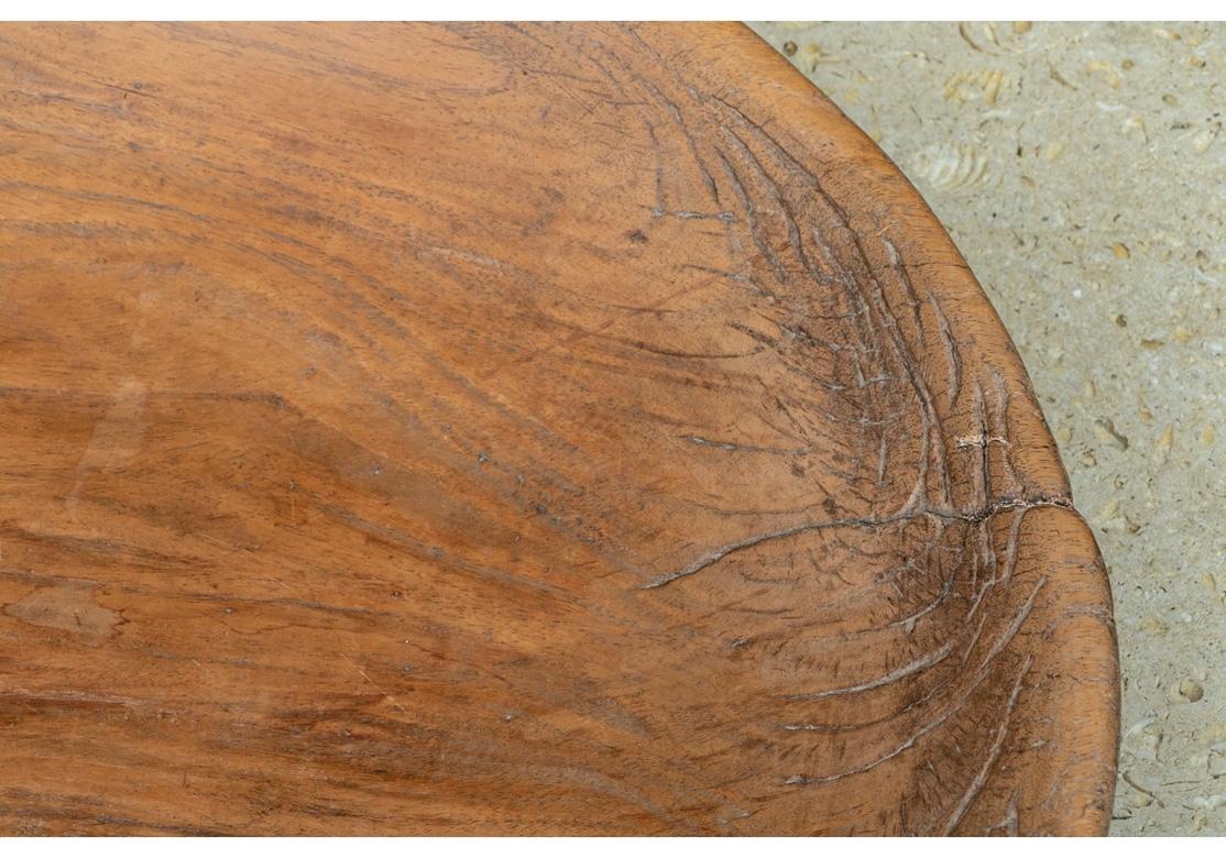 A fine and large rustic dough bowl in all original as found condition, with subtle graining, presumed to be Elm. The Bowl is unusually shallow and a full 24.75” diameter, made from a single wood section. Fine timeworn and age softened feel. 
The