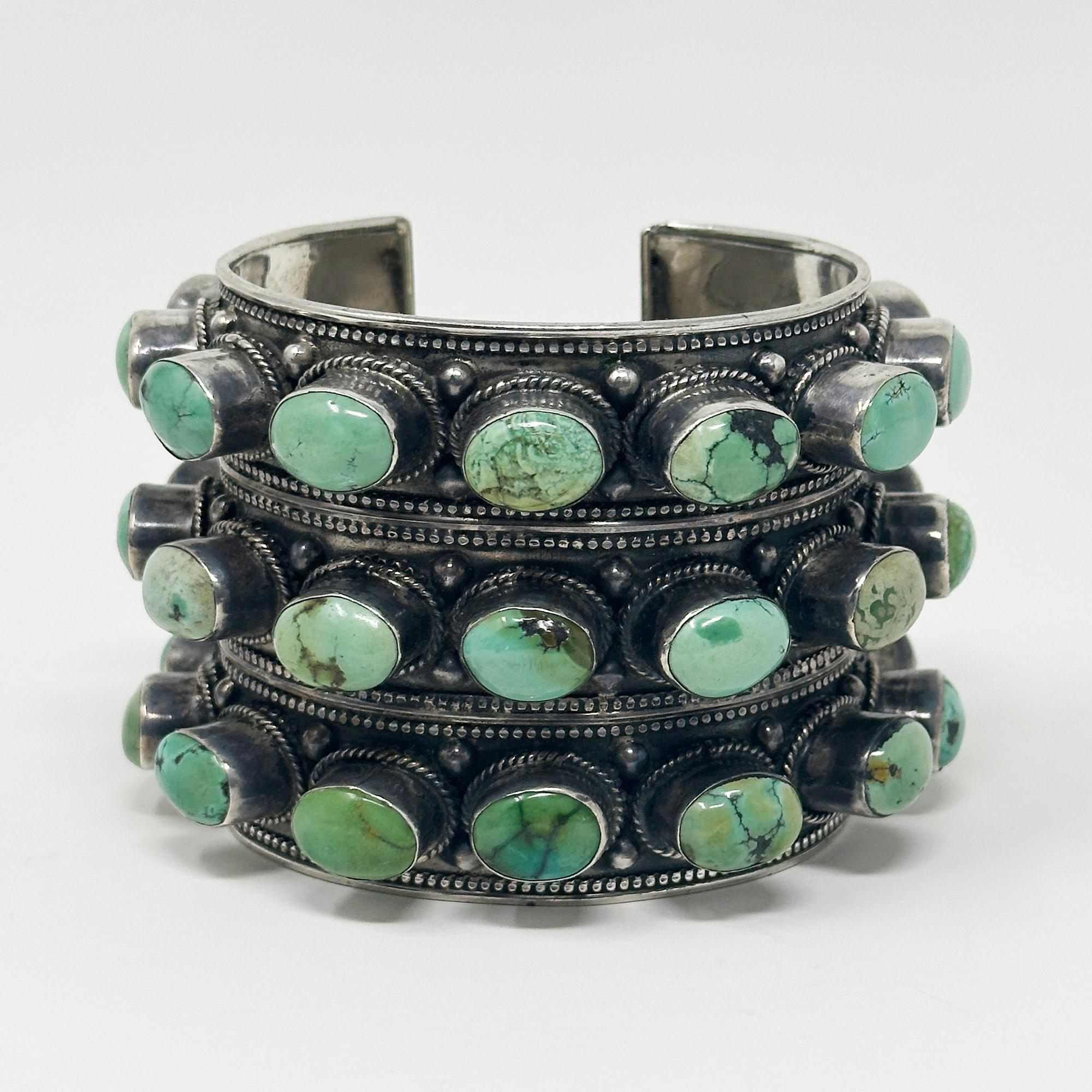 Polsino in argento e turchese borchiato del XX secolo

Un enorme bracciale con borchie in argento e turchese, realizzato da argentieri nepalesi nella seconda metà del XX secolo. Ci sono trentatré cabochon ovali di turchese incastonati in tre file. 