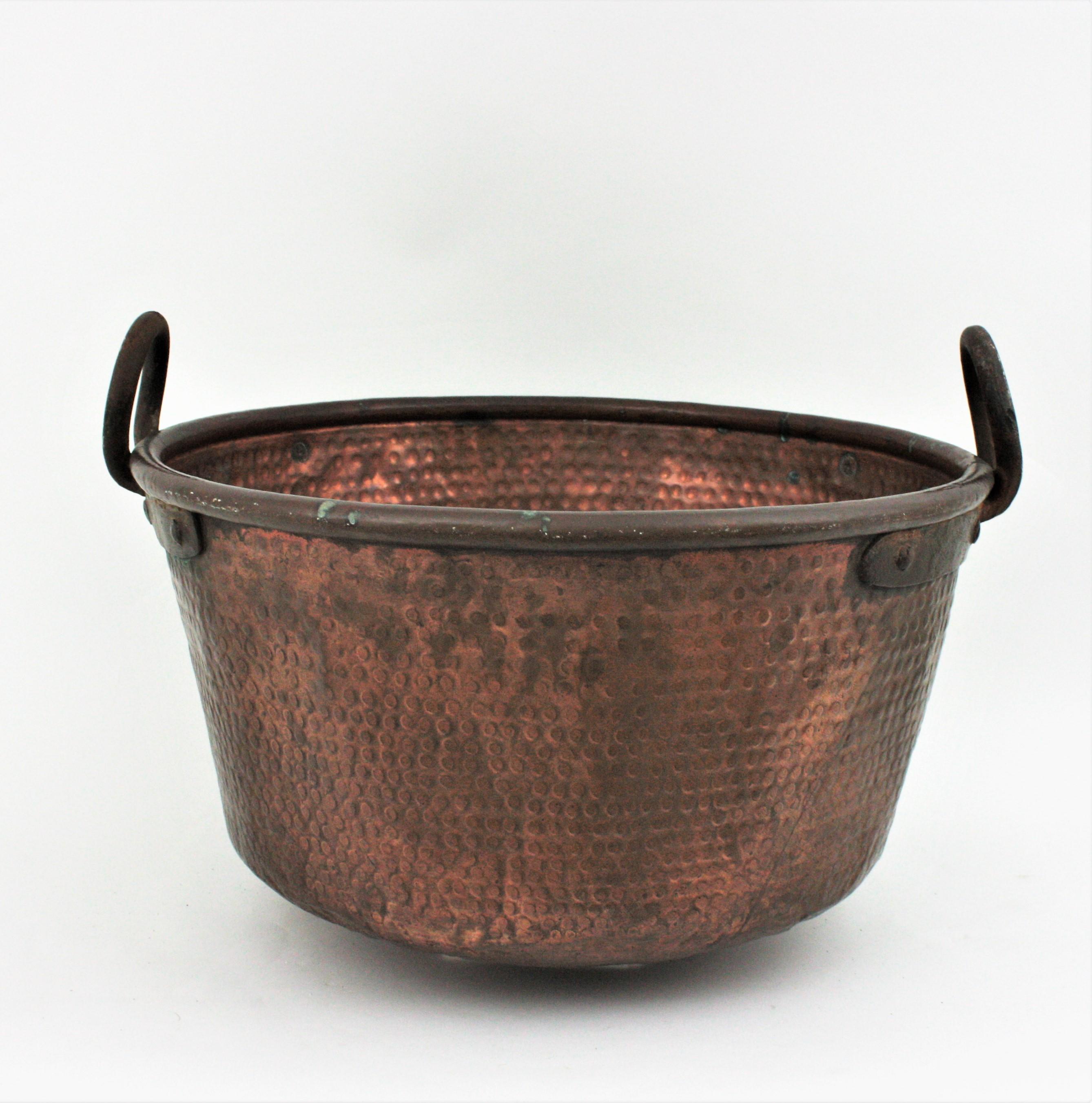 Oversized hand-hammered copper cauldron with iron handles, Spain, 1920s.
This handcrafted copper cauldron has a dramatic aged patina. The copper is heavily marked by the pass of time and it has a strong visual effect.
The iron handles are attached