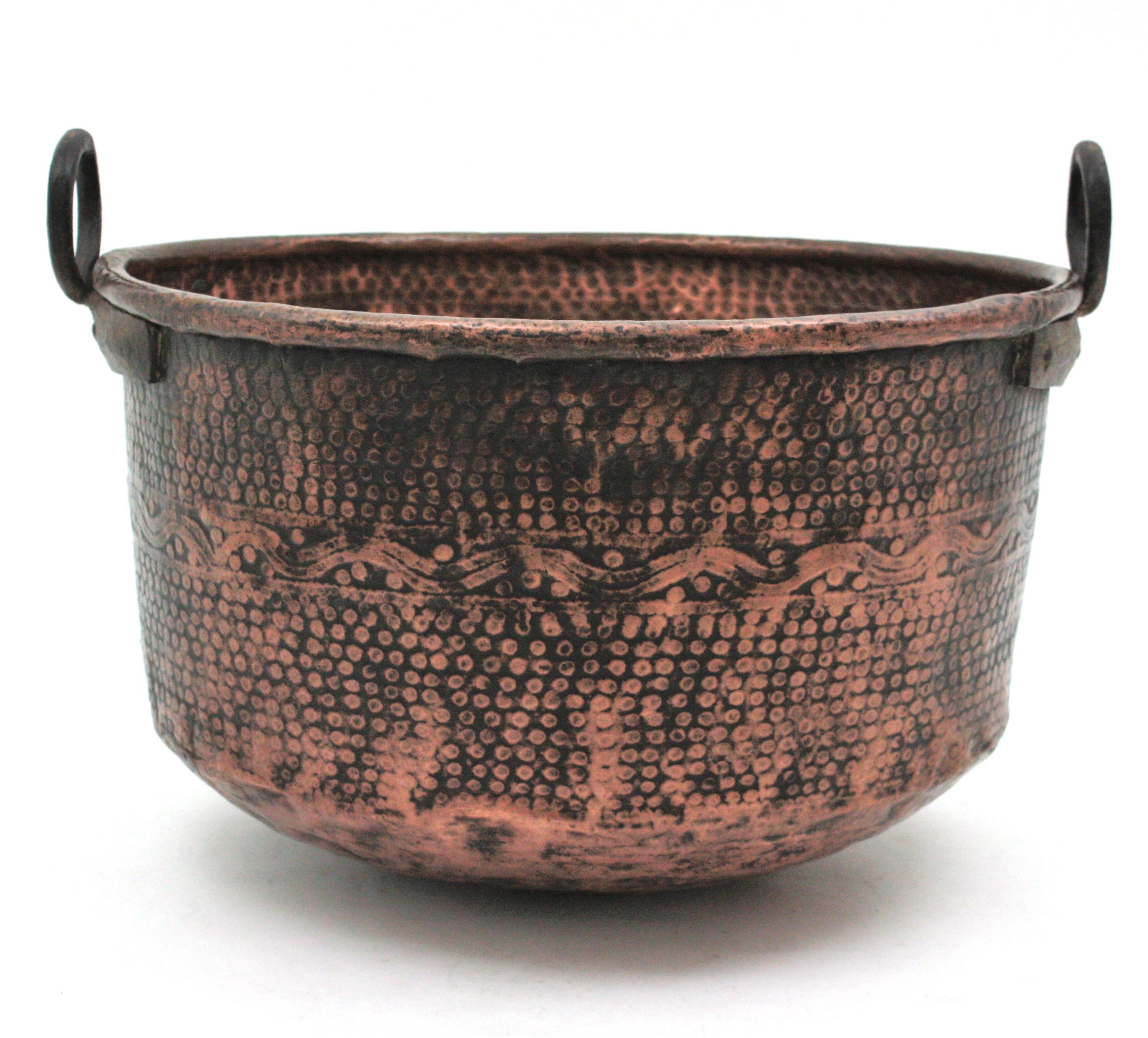 Oversized hand-hammered copper cauldron with iron handles, Spain, 1930s-1940s.
This handcrafted copper cauldron has a dramatic aged patina. The copper nicely addorned by decorative hand hammered patterns and it is heavily marked by the pass of time