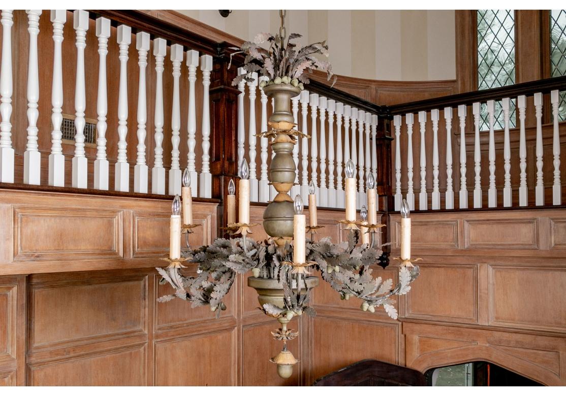 A tall three part turned standard in taupe brown and tan tones topped by a fan of taupe tole leaves. The two tiers of lights with clusters of coordinating brown taupe tole oak leaves and pendant acorns along the light arms. The lights with tan tone