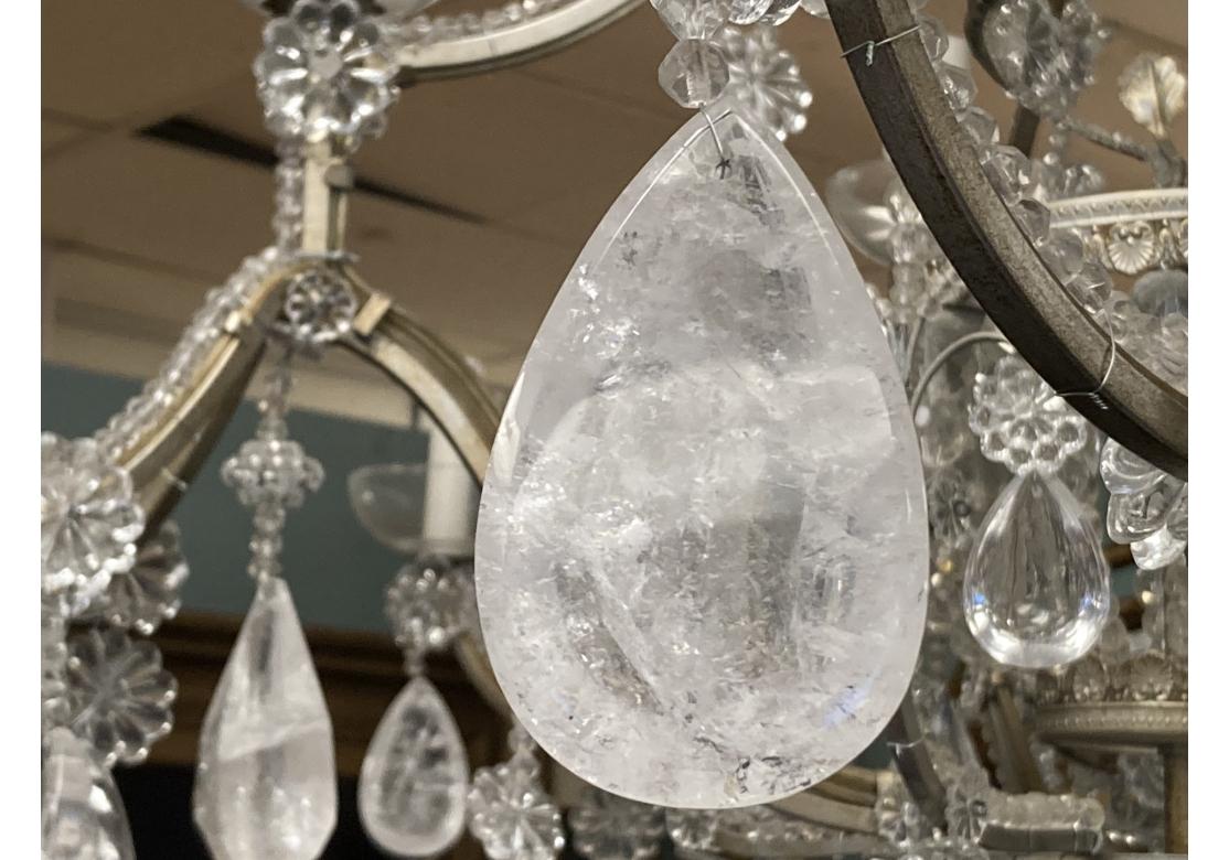 A very fine 12 light chandelier crested with a true corona with clear crystal and rock crystal pendants emitting from a beaded crown. Four scrolling arms laden with crystal beads surround the foliate spiral standard and lower graduated beaded