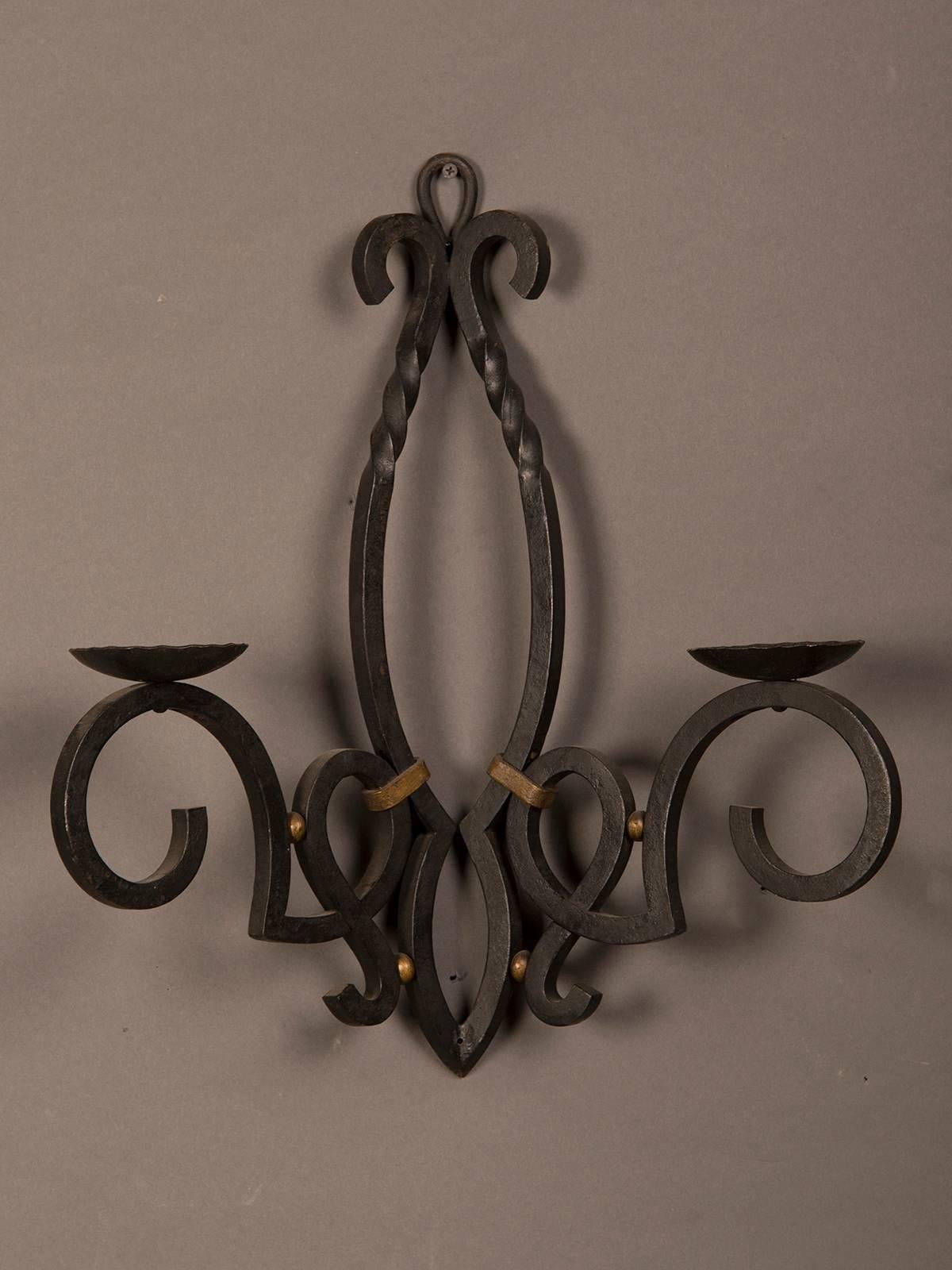 A massive vintage French hand-forged iron wall sconce with gilded highlights having a pair of candle cups ready to be electrified and mounted on a wall from France, circa 1940.