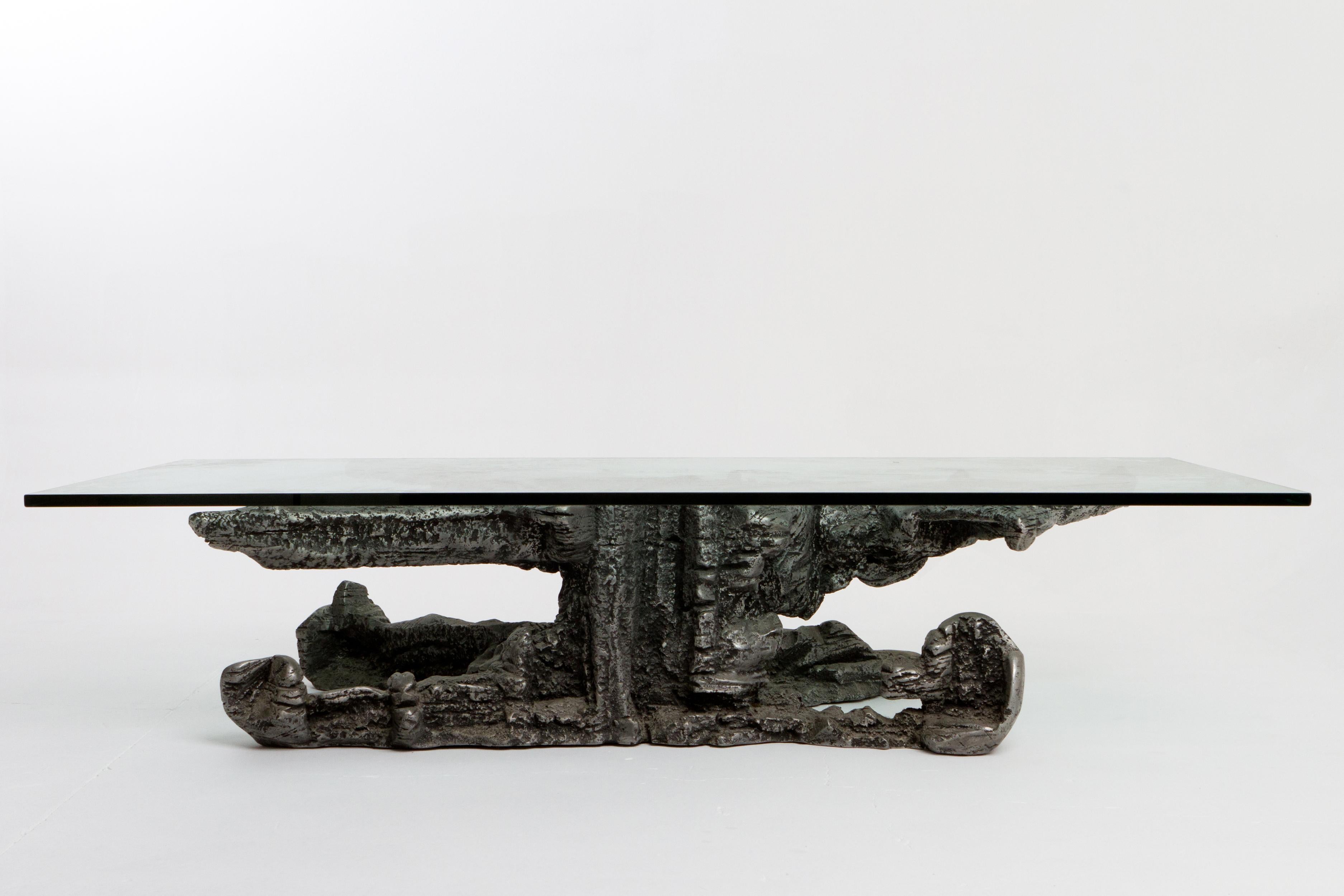 Table basse massive en fonte d'aluminium et plateau en verre. Vendue en aluminium, la base pèse environ 200 livres. Esthétique sculptée avec des formes organiques, imitant quelque peu les rochers, les racines, etc. Le verre est d'origine et en bon