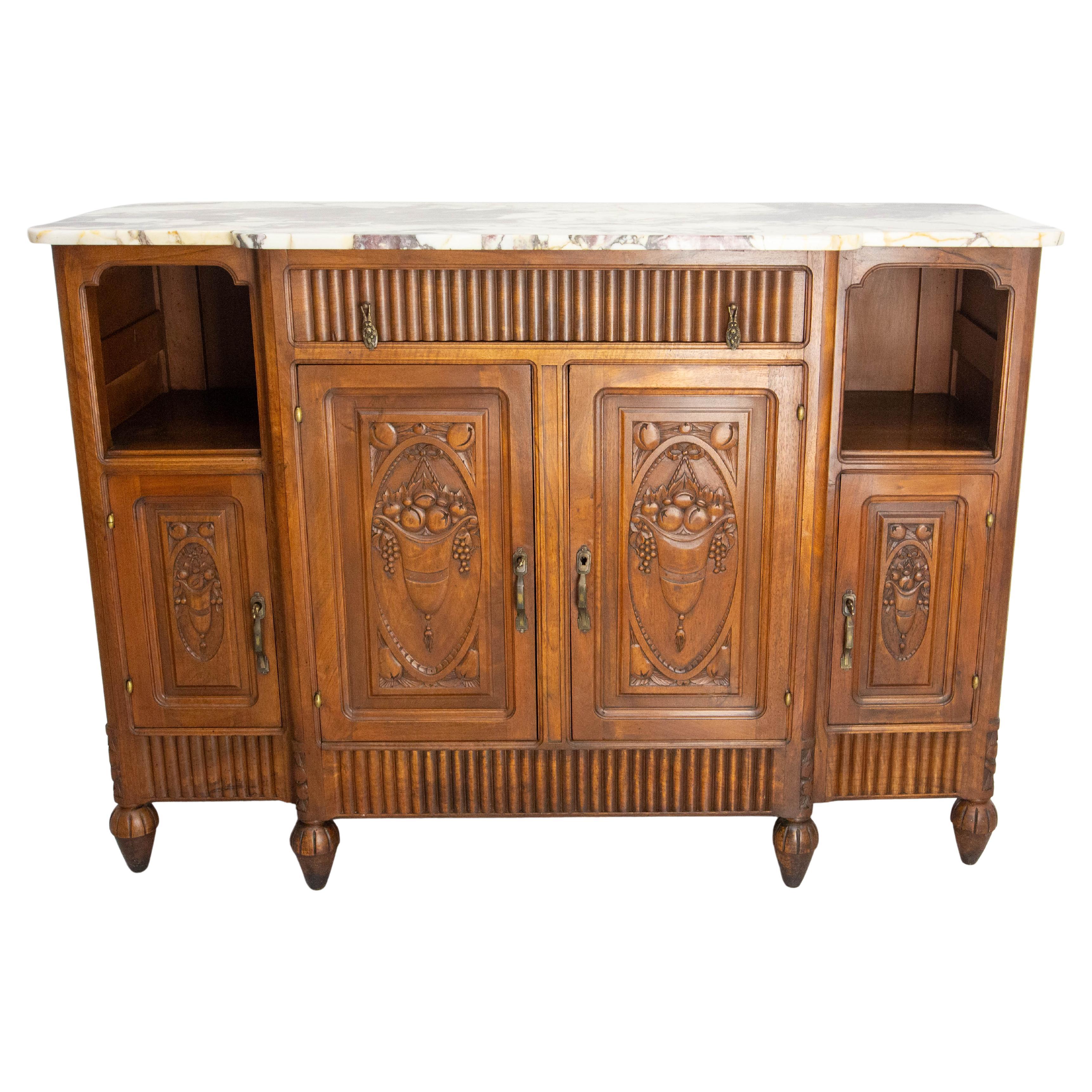 French credenza buffet made circa 1920.
Walnut and caracatta marble white and violet with yellow marbling.
One drawer, four doors and two niches.
The doors are hand caved with hanging fruit baskets.
Very décorative item. Few marks of use and of the