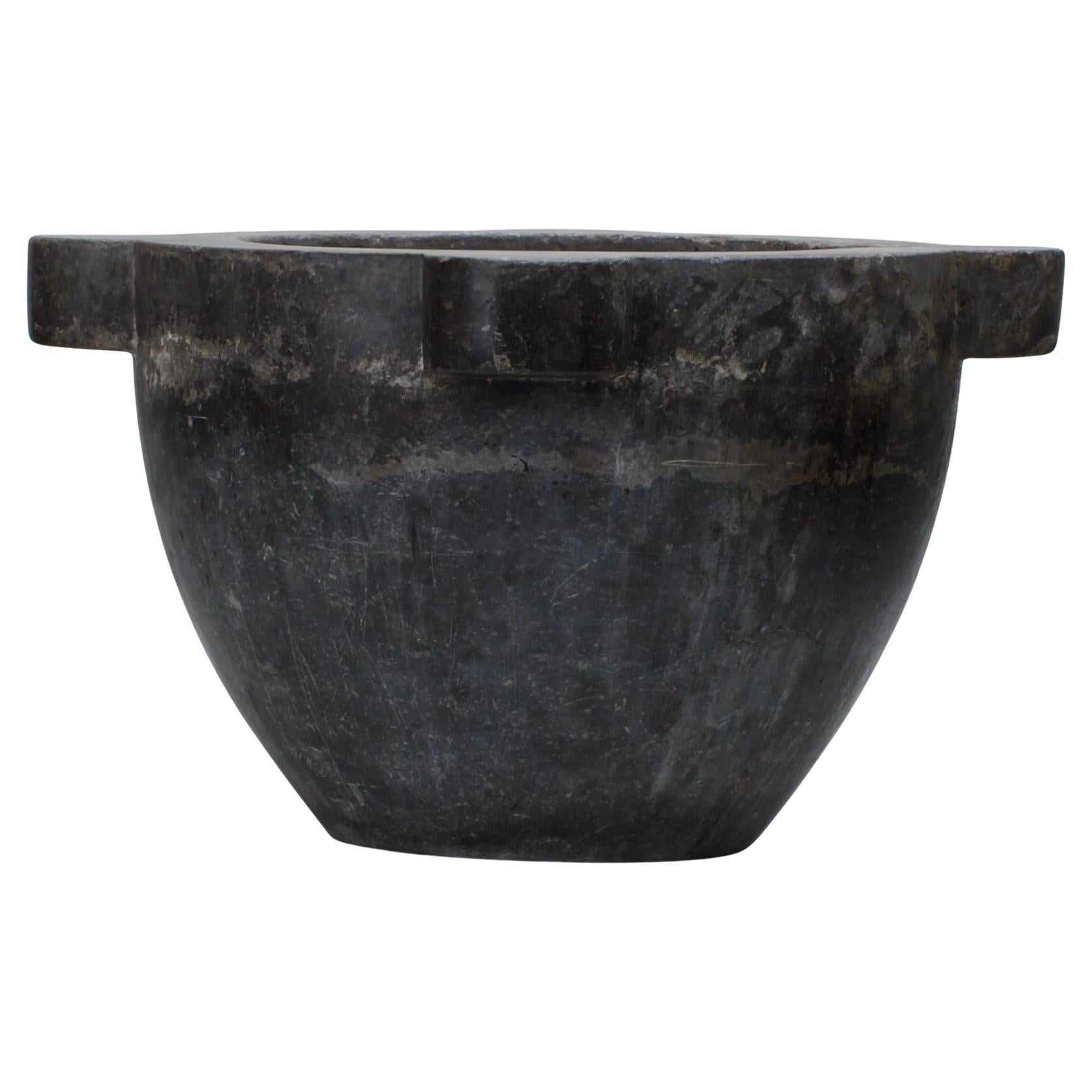 This Massive 17th-century granite mortar is an impressive and substantial piece, showcasing both functionality and artistry. Crafted from solid granite, its unique color palette and patina reflect centuries of use, giving it a rich historical