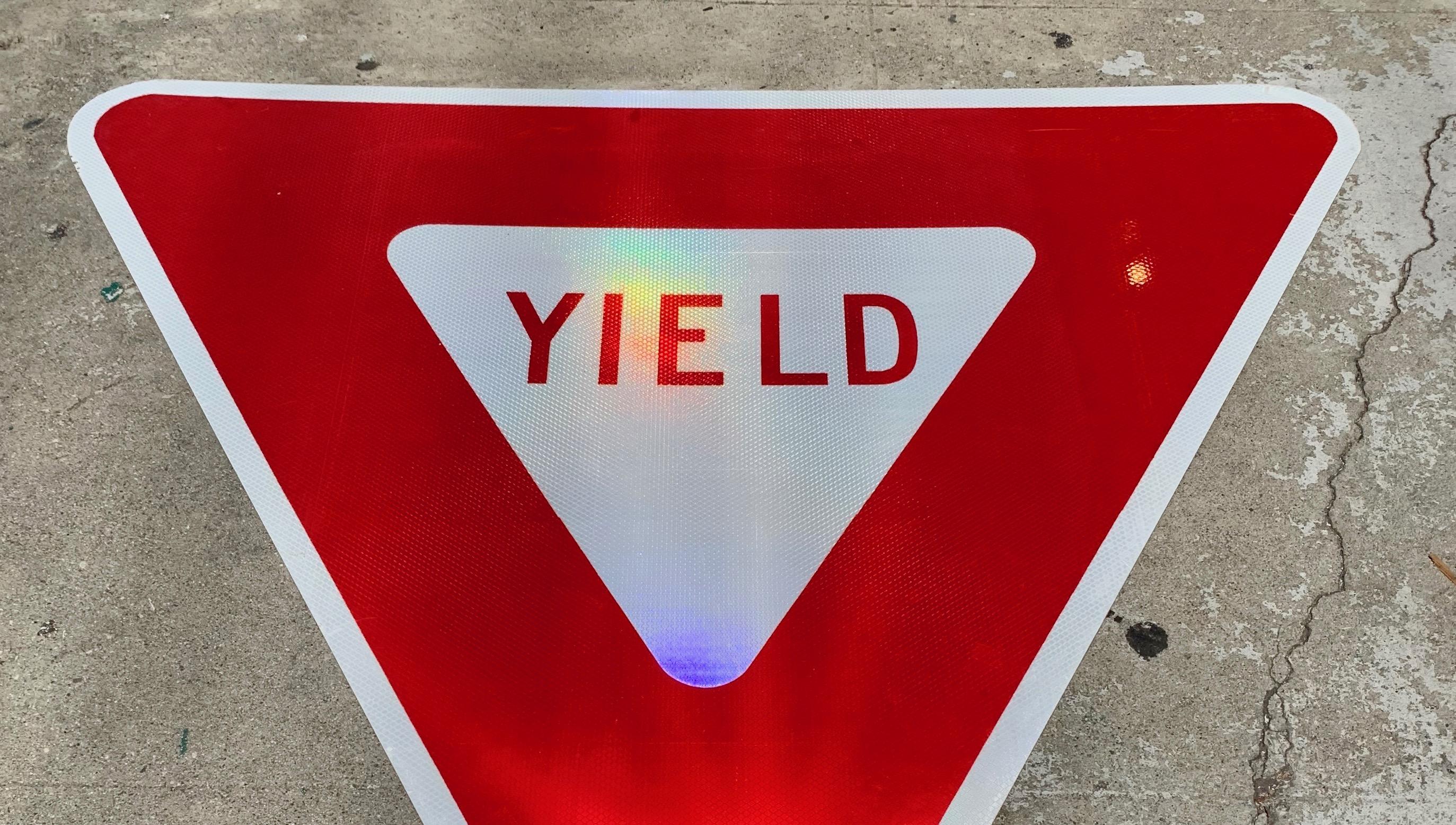 Massive 'YIELD' road sign. Red steel sign with red letters and white triangle. Cool piece of highway ephemera. Good vintage condition. Fun piece of wall art.