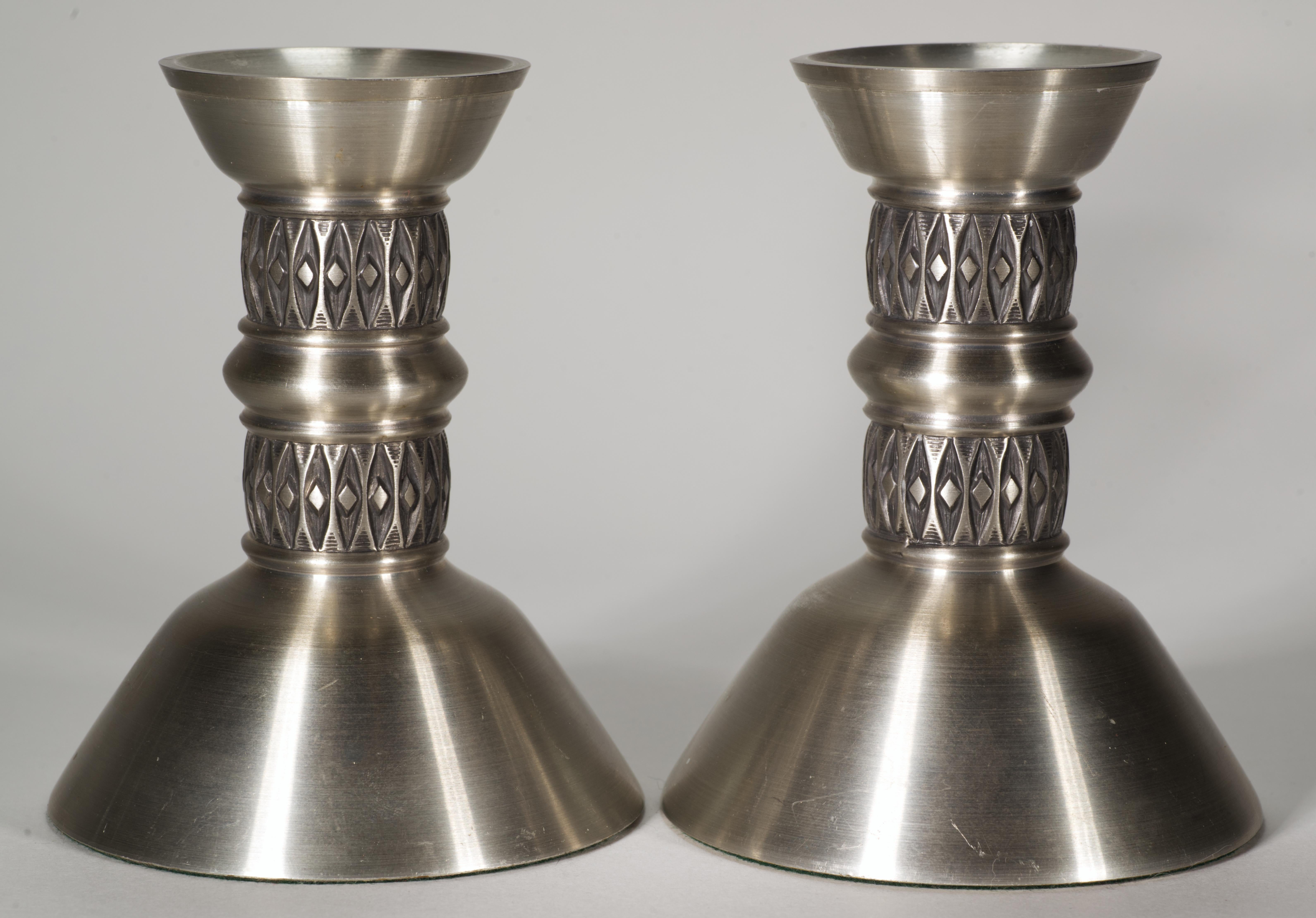  Rare pair of sculptural pewter candle holders in Scandinavian Midcentury Modern style was made by Mastad Norway in 1950s. Each candle holder has built-in bobeche to prevent wax drippage, slightly elongated body with two bands of abstract patterns,