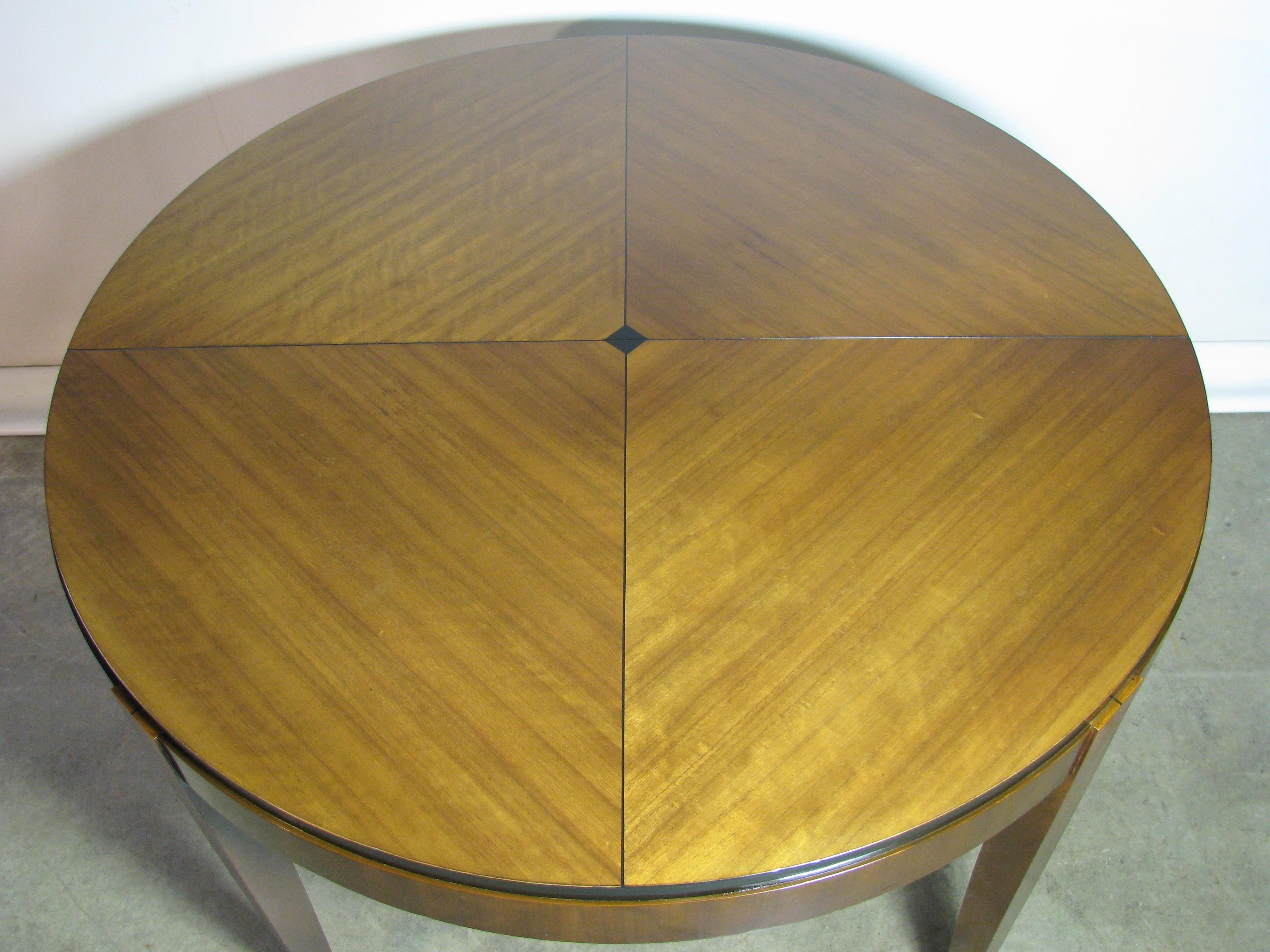 Spectacular vintage Mastercraft dining table in the Postmodern/Art Deco style. Beautifully figured veneers create an angled pattern on the circular top, centered around an ebonized diamond. The skirt of the table is vertical, with a stepped back