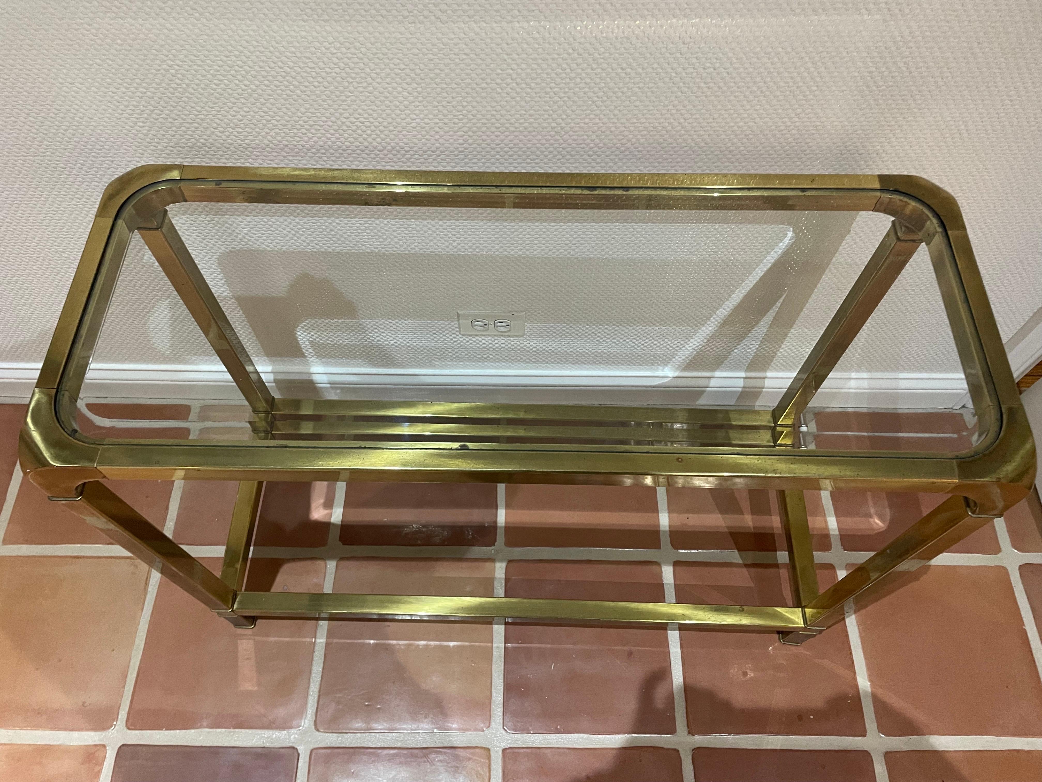 This is a mid size brass and glass vintage Mastercraft console table in nice vintage condition. Has some oxidation on brass but no dents to metal 