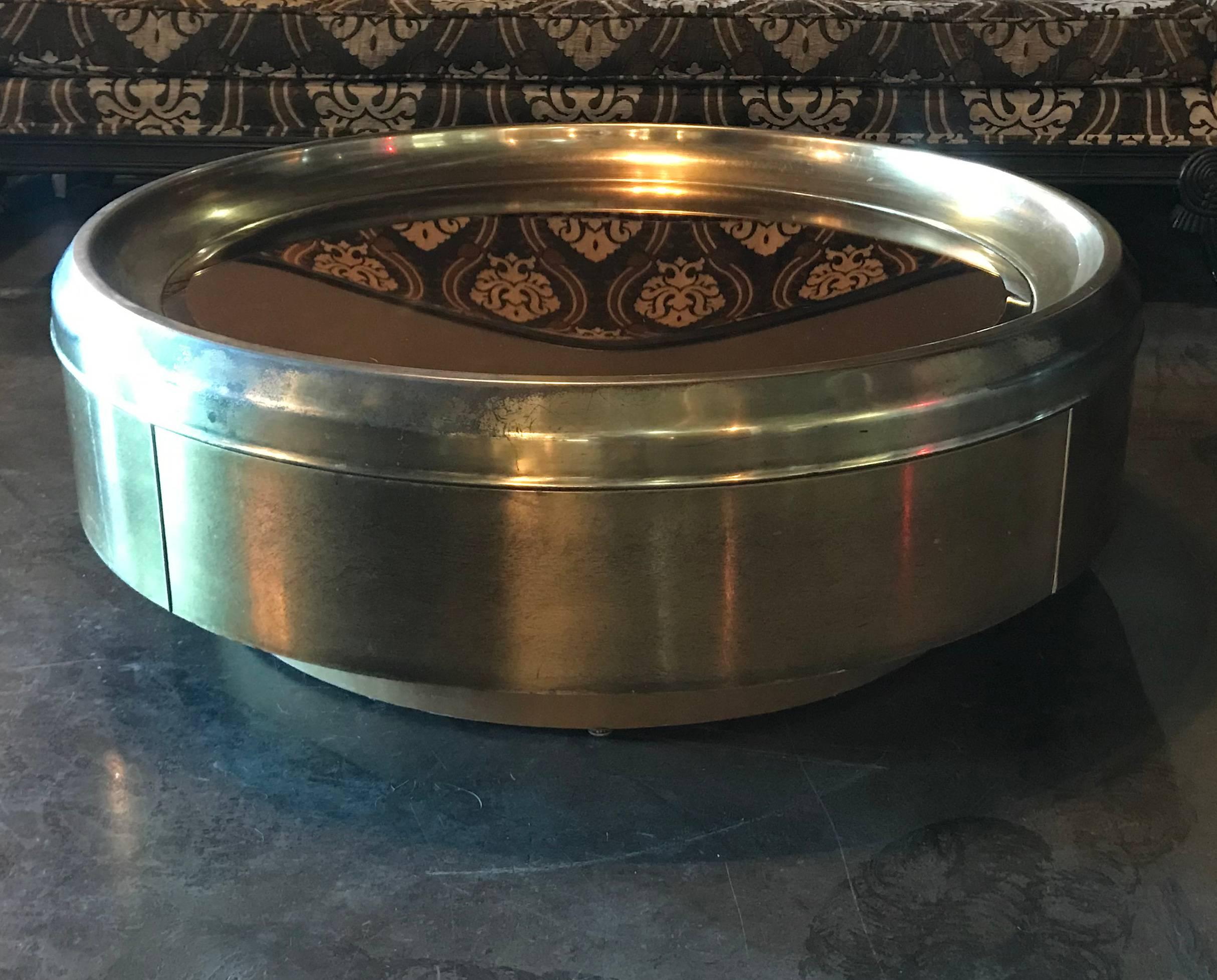 This table is absolutely stunning example of Mid-Century Modern design by Mastercraft. This canister brass coffee table features a gorgeous heavily patinated brass body with a brass tinted mirrored top.