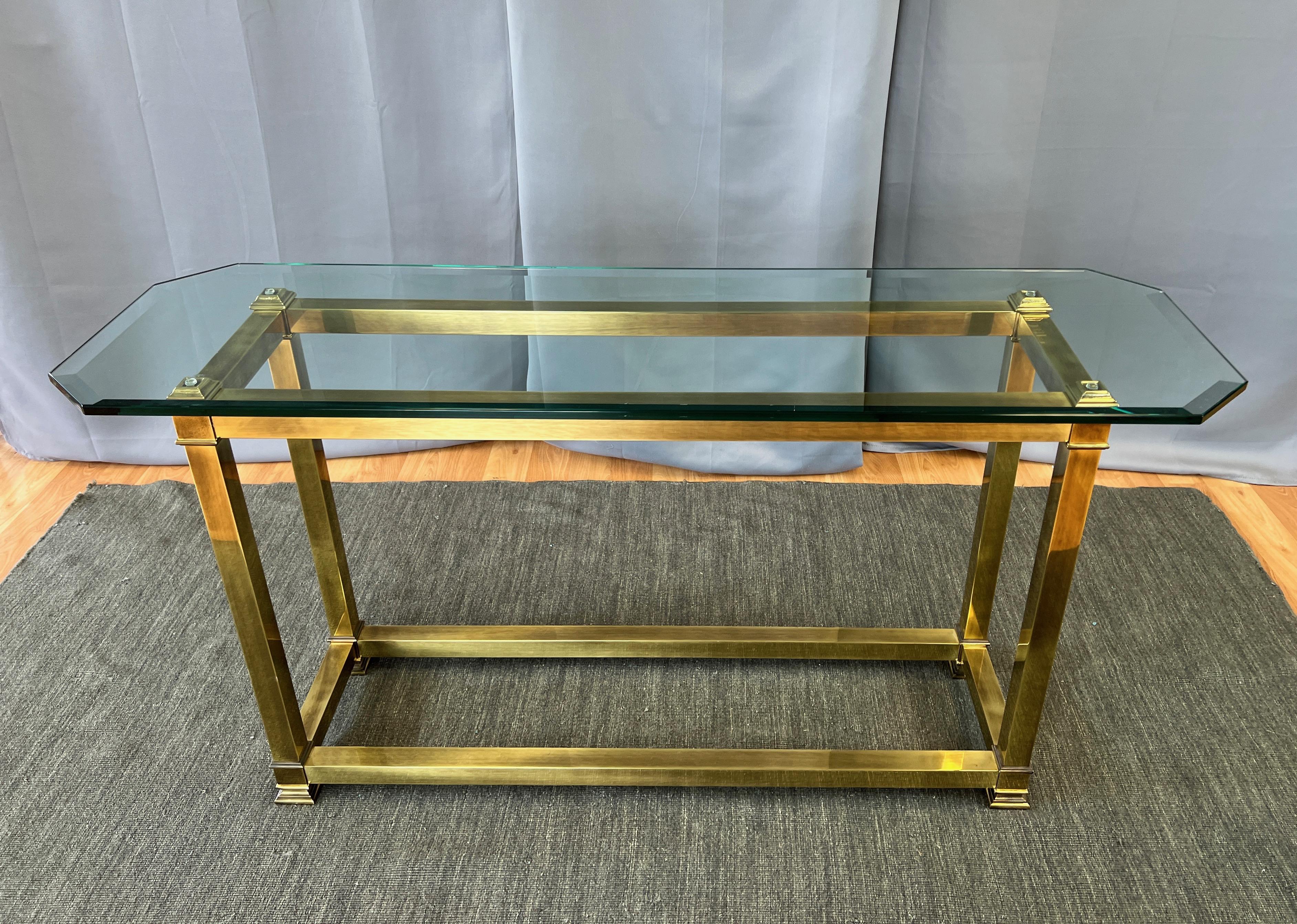 An uncommon 1970s Mastercraft brass console table with thick beveled edge glass top.

Very handsome Hollywood Regency design features substantial square tube frame elements with classical-style top corner and foot details. Displays Mastercraft’s