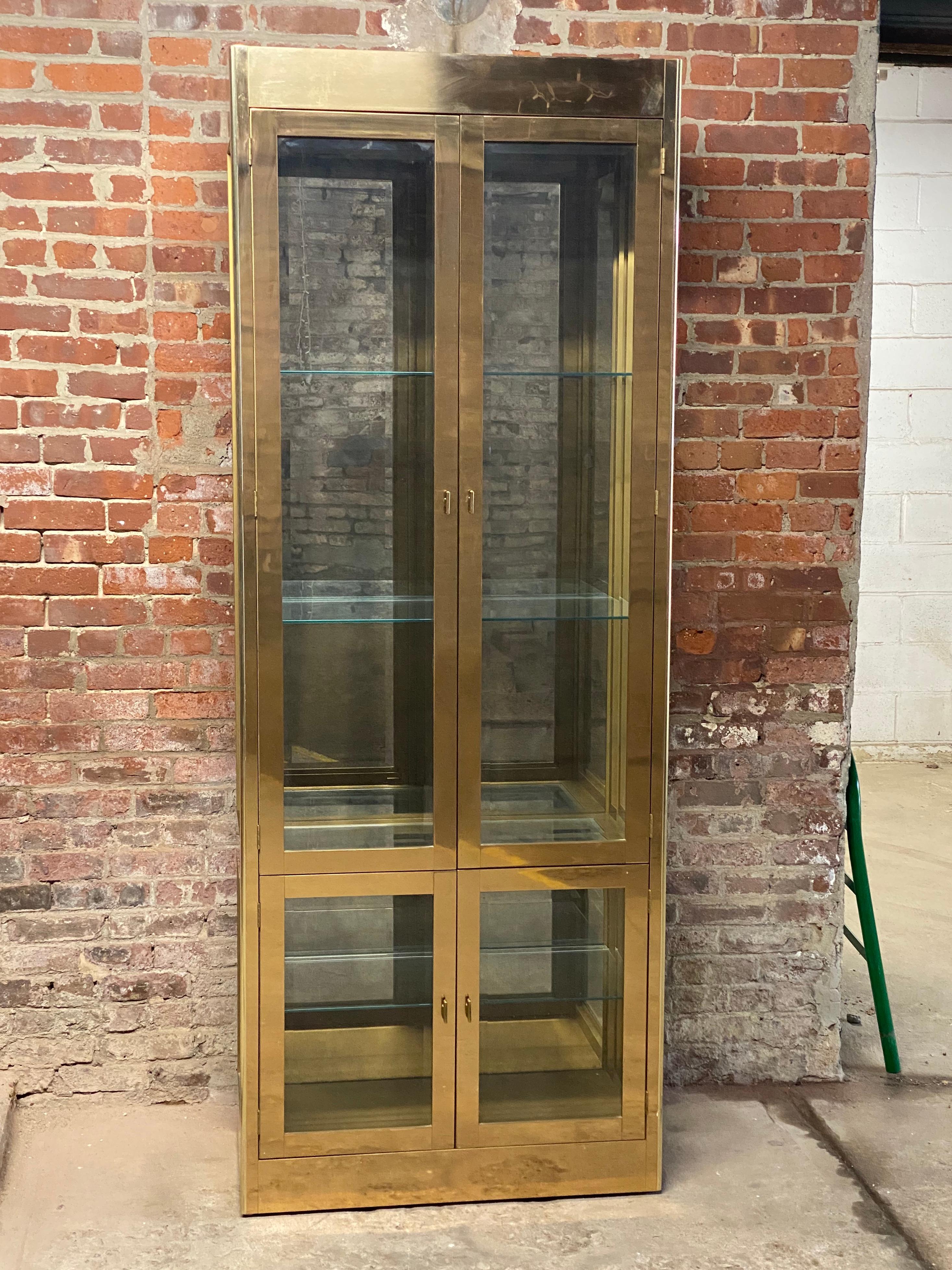 Brass and glass Mastercraft display cabinet designed by Bernhard Rohne. Brass clad cabinet, mirrored back, beveled glass panels and adjustable height glass shelves. The ultimate luxury display cabinet for your valuables and collectibles. Signed on