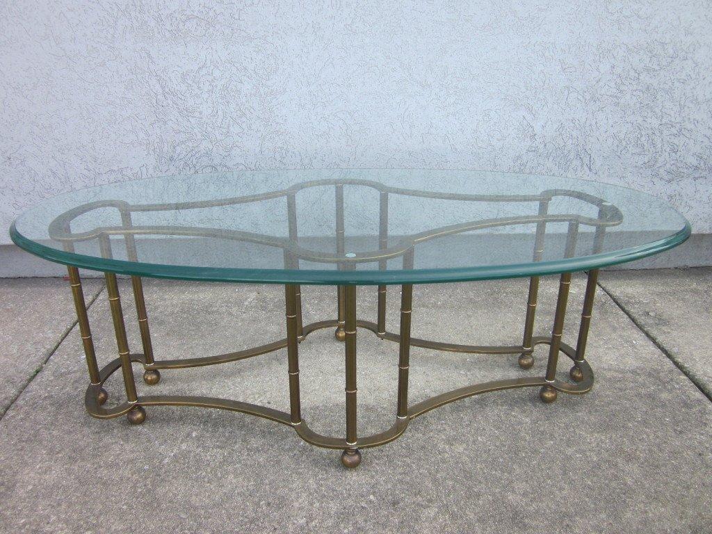 Mastercraft brass faux bamboo coffee table. Has a beveled oval shaped glass top with a brass, decorative faux bamboo base.
The length listed is inclusive of glass top.
