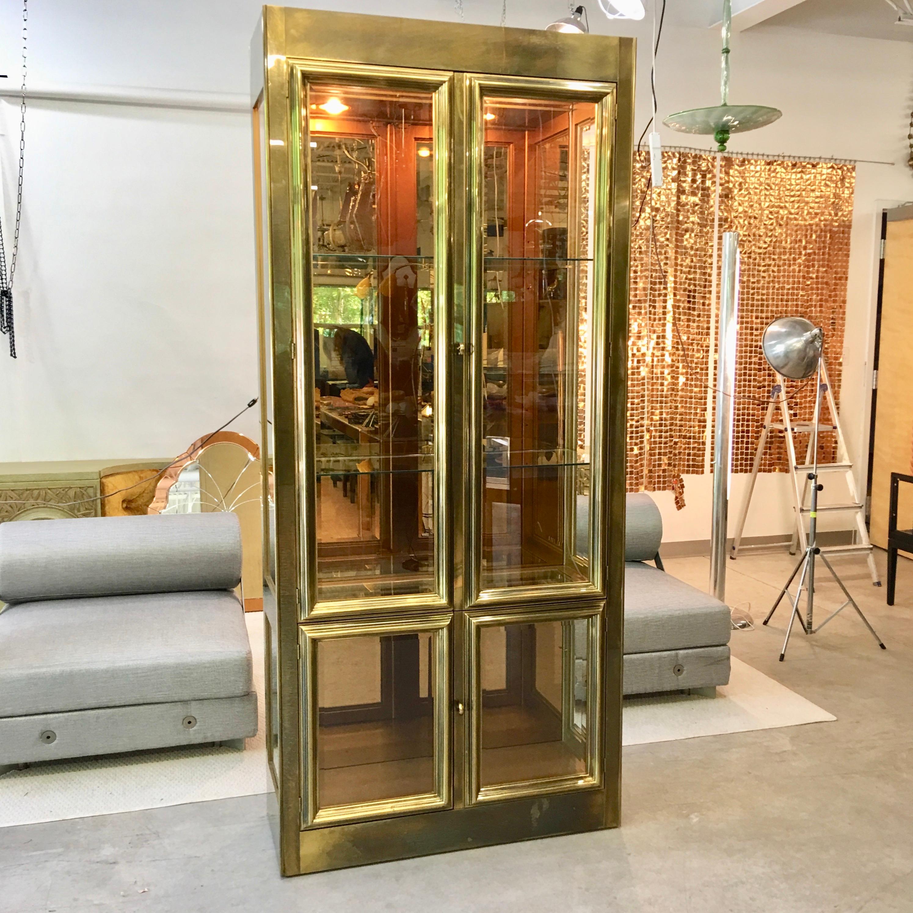 Four door brass vitrine display case by Mastercraft of Grand Rapids, Michigan circa 1970. Upper case with two tall doors; lower case with two short doors; all doors with beveled glass framed in heavy brass moulding. Upper and lower sidelight windows