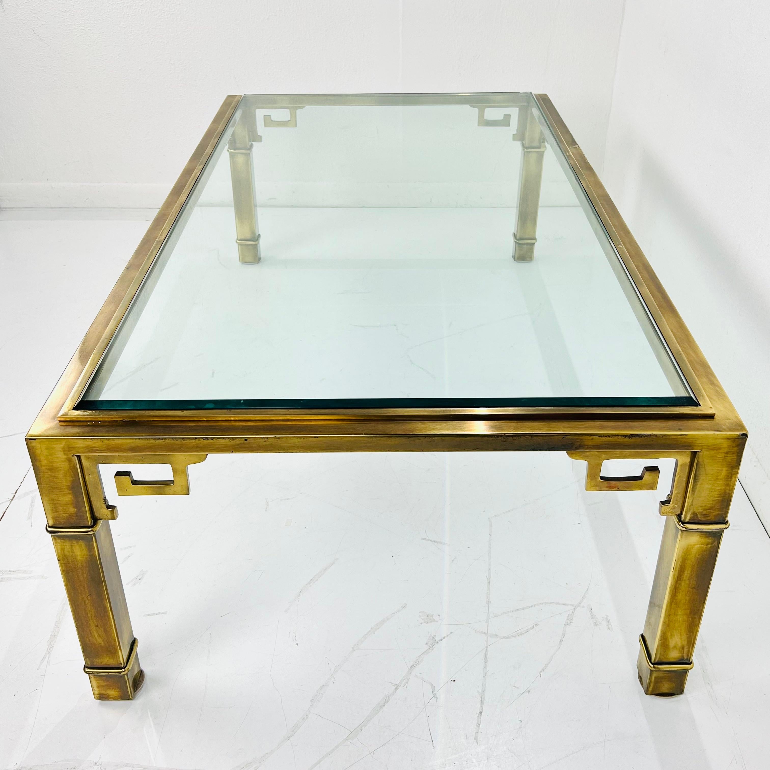 Iconic long and low rectangular brass and glass Greek key coffee table, made in Italy for Mastercraft Grand Rapids, MI, circa mid-twentieth century. Good condition with beautiful patina; glass has some chips at edge (pictured) - Glass top will be