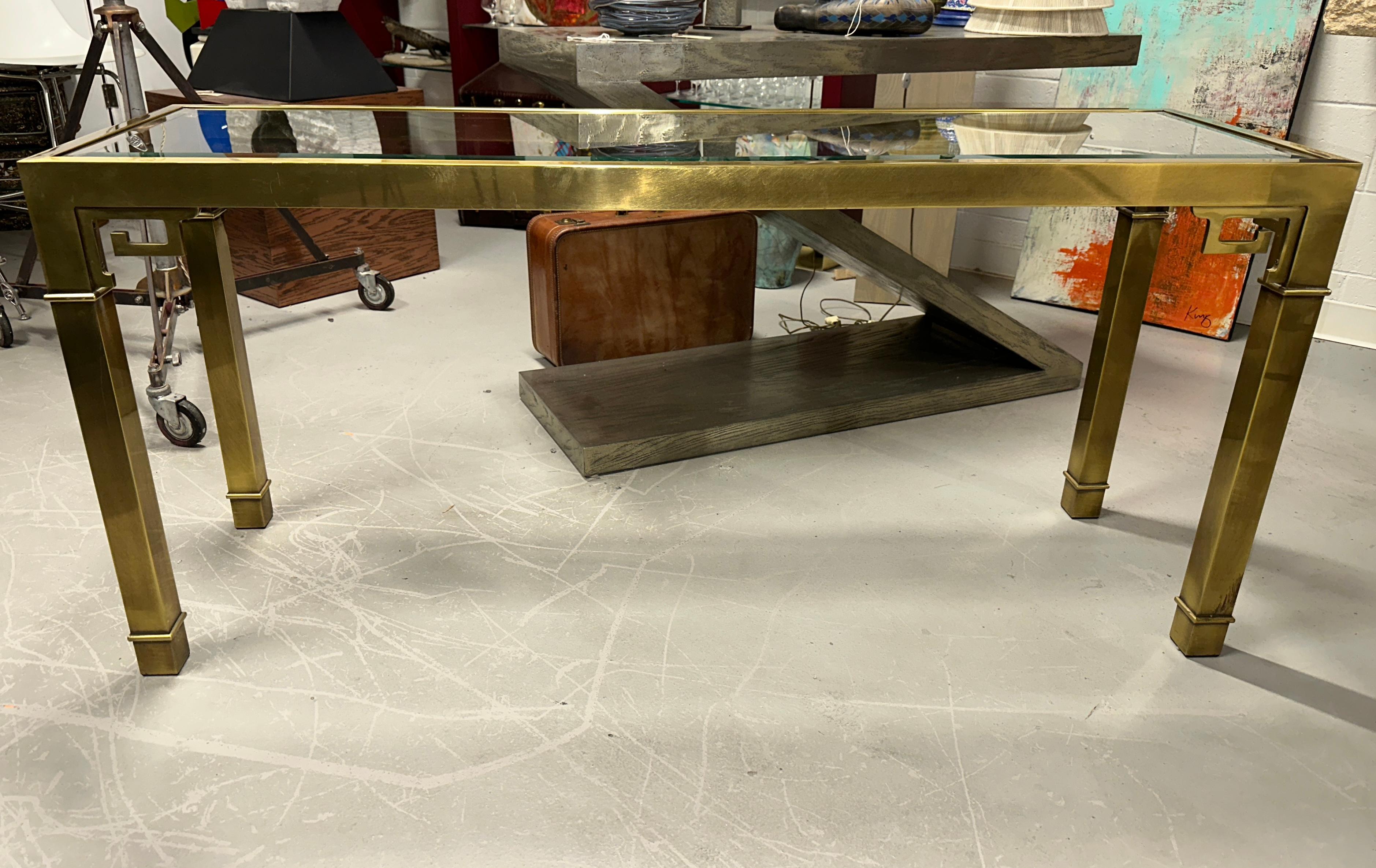 Nice greek key motif brass console or sofa table by Mastercraft. The glass top is bevelled. The table is in good vintage condition, but does have some scratches and surface imperfections detailed in the pictures. There is a flaw in one corner of the
