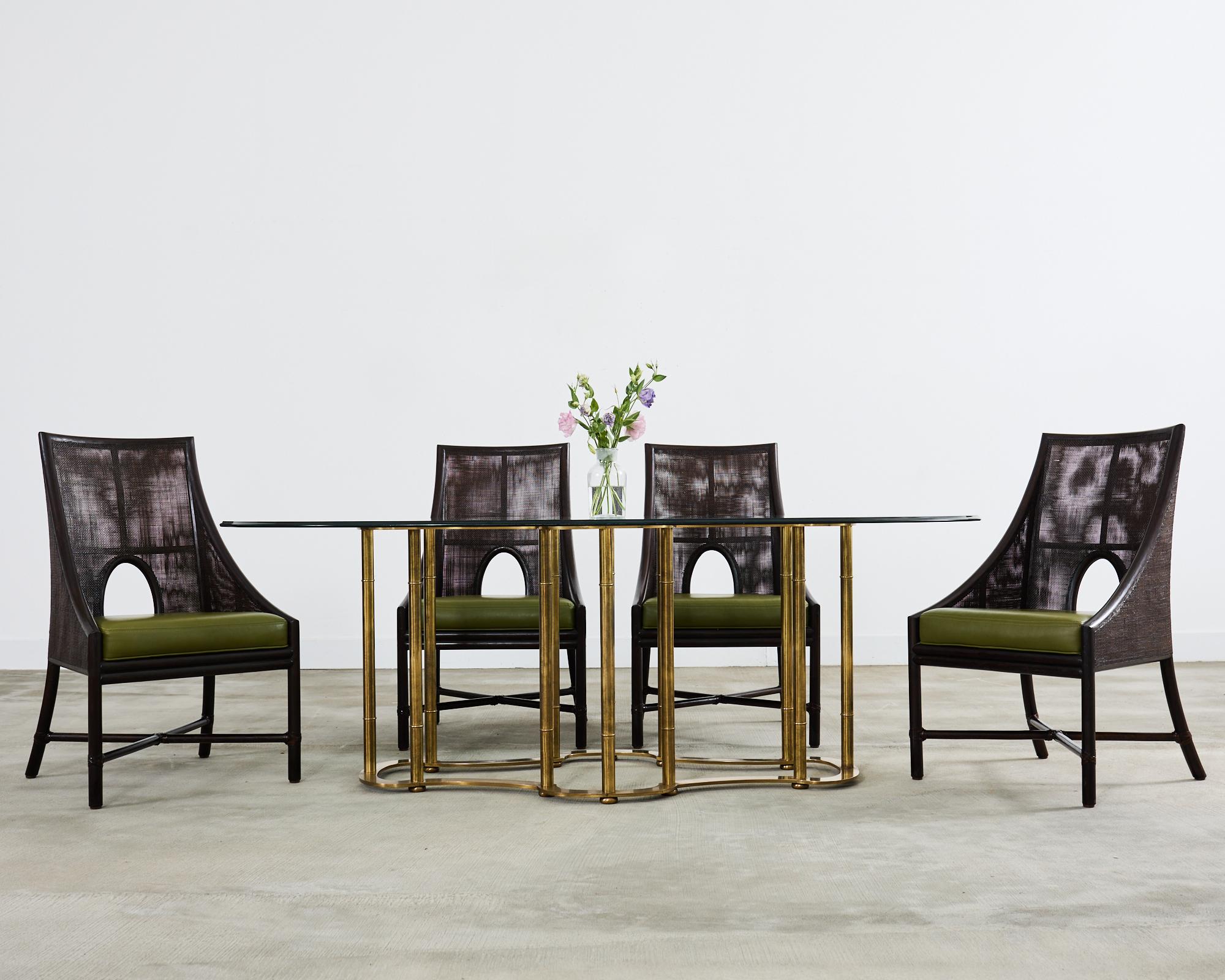 Iconic Italian regency brass racetrack dining table made by Mastercraft. The table features a cast solid brass base in the form of an elongated quatrefoil or racetrack. The base has 12 faux bamboo legs that support a thick 7' foot long pane of