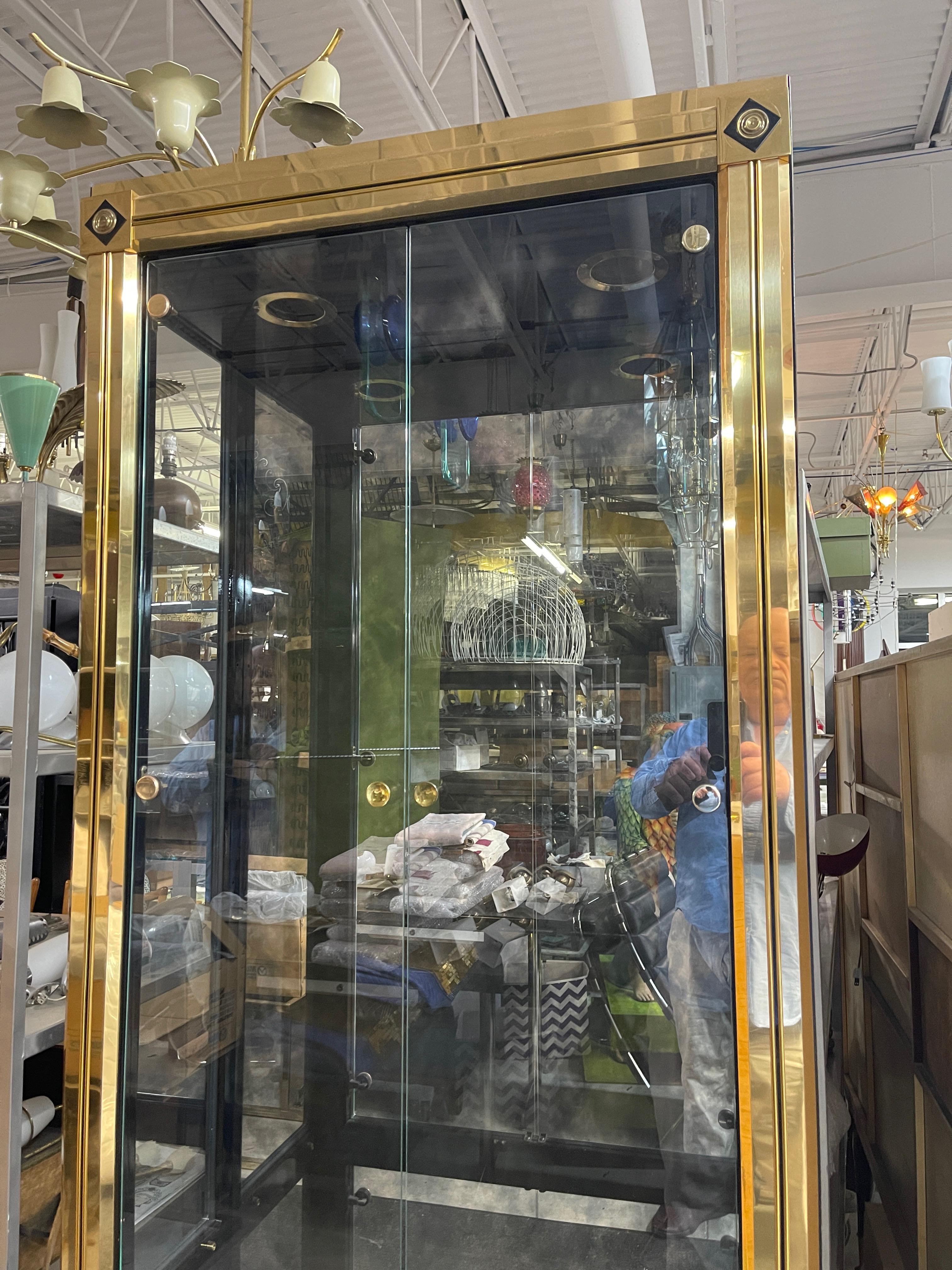 Uncommonly seen Model 280 polished brass vitrine china display cabinet, designed by William Doezema and executed by Mastercraft of Grand Rapids circa 1970, 
Four glass doors, three adjustable glass shelves with groove for plate or picture display