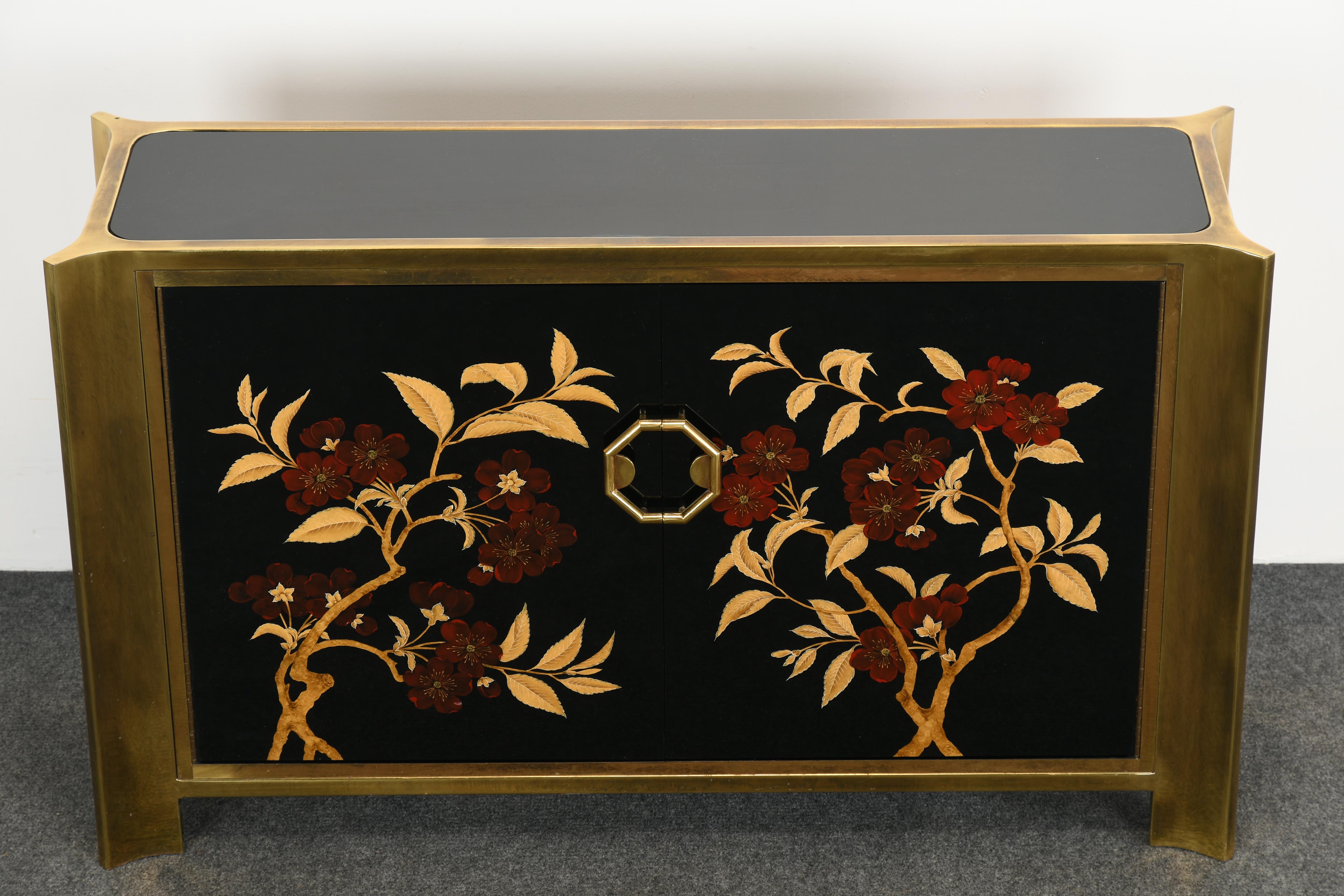 A gorgeous Mastercraft cabinet or console with monumental brass frame and floral design front. The cabinet size is a wonderful petit design that would work in almost any space such as a hallway or entryway. The black lacquer and details on the front