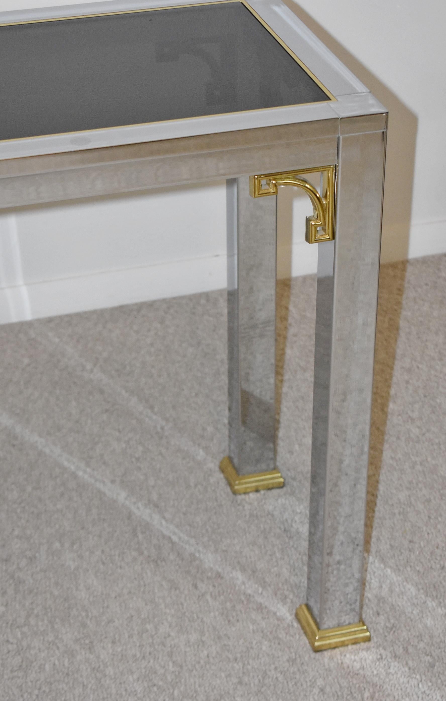Mastercraft chrome console table. Circa 1970s. Square tubular legs with brass feet. 3 Smoked glass top panels. Brass corner braces. Mid-Century Modern Style. Great condition, wear consistent with age and use. Dimensions: 60