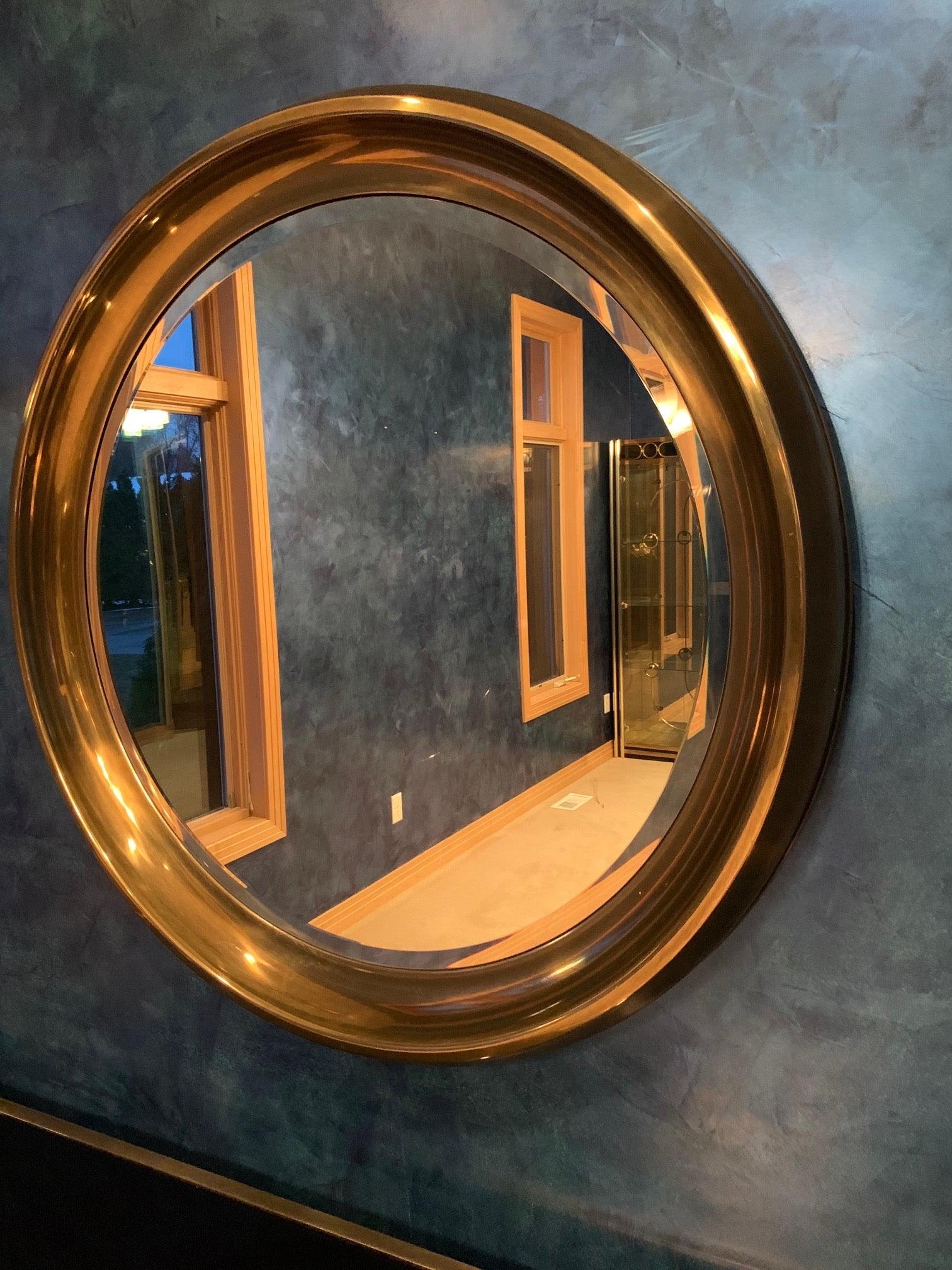 Oversize vintage 1970's mirror by William Doezema for Mastercraft in a wide rimmed patinated brass moulded frame featuring an inset circular beveled mirror.
  