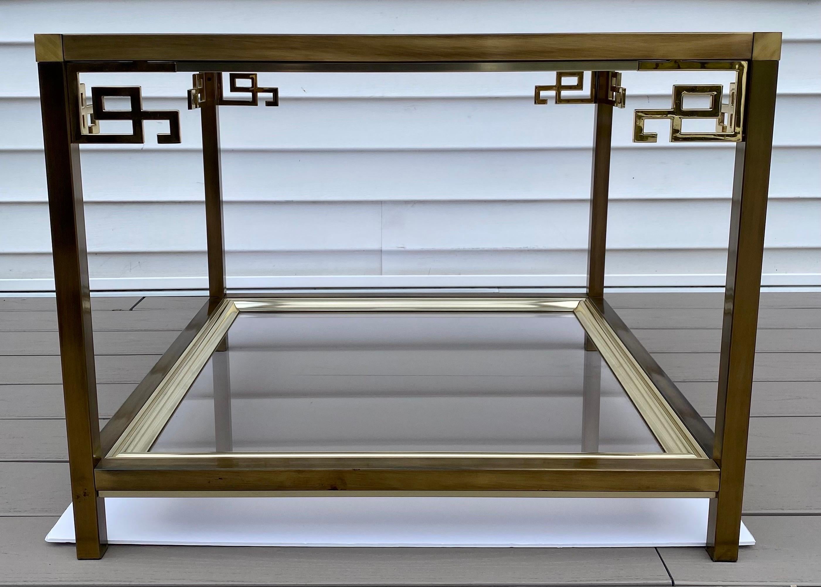 Mid-Century Modern Greek key smoked glass and brass side or coffee cocktail table by Mastercraft. This two-tier square shaped table features removable smoked glass inserts framed in brass.