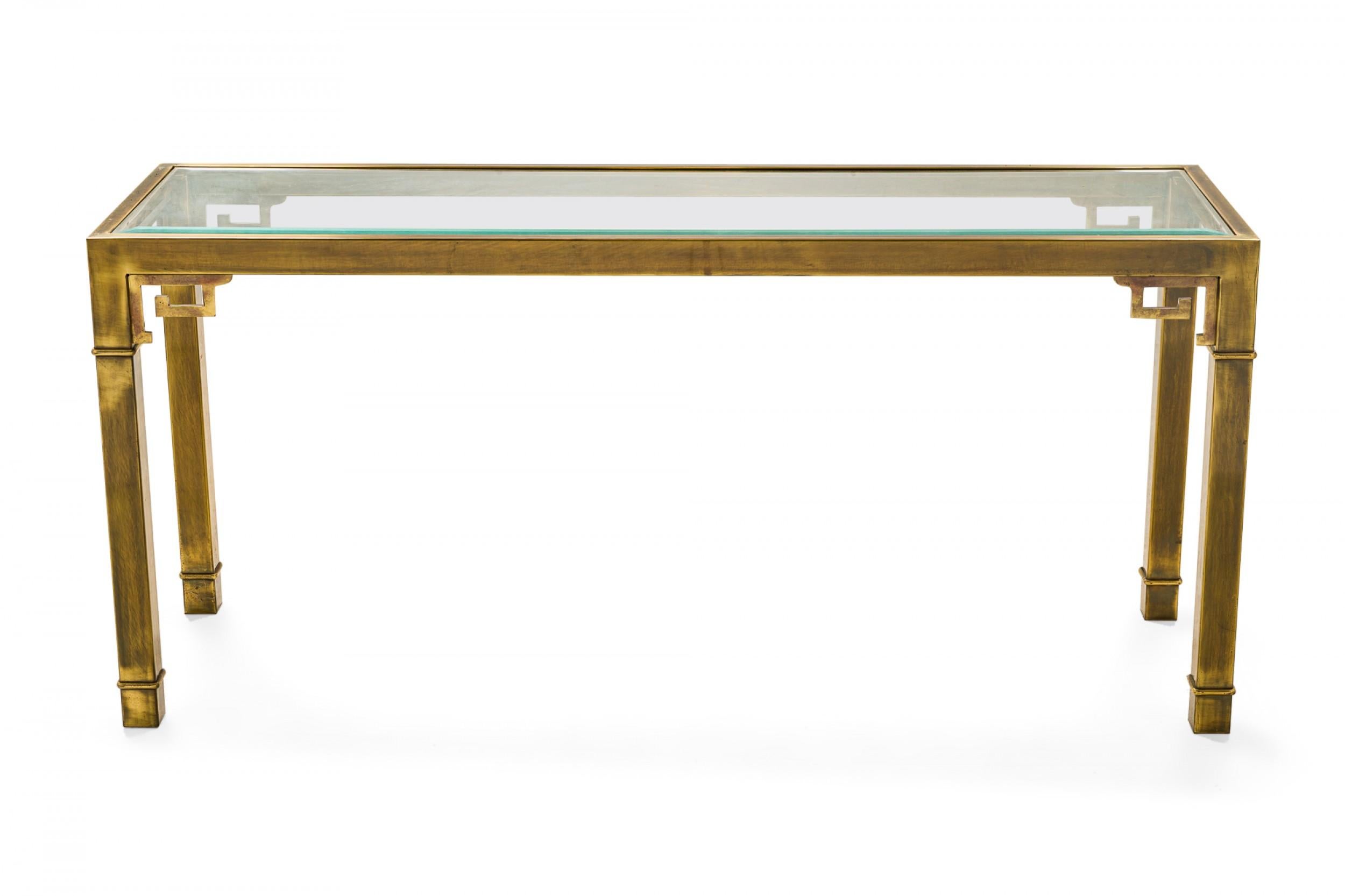 Mid-Century rectangular console table with an antiqued brass frame featuring a Greek key design apron, and an inset glass top resting on four square brass legs. (Mastercraft).