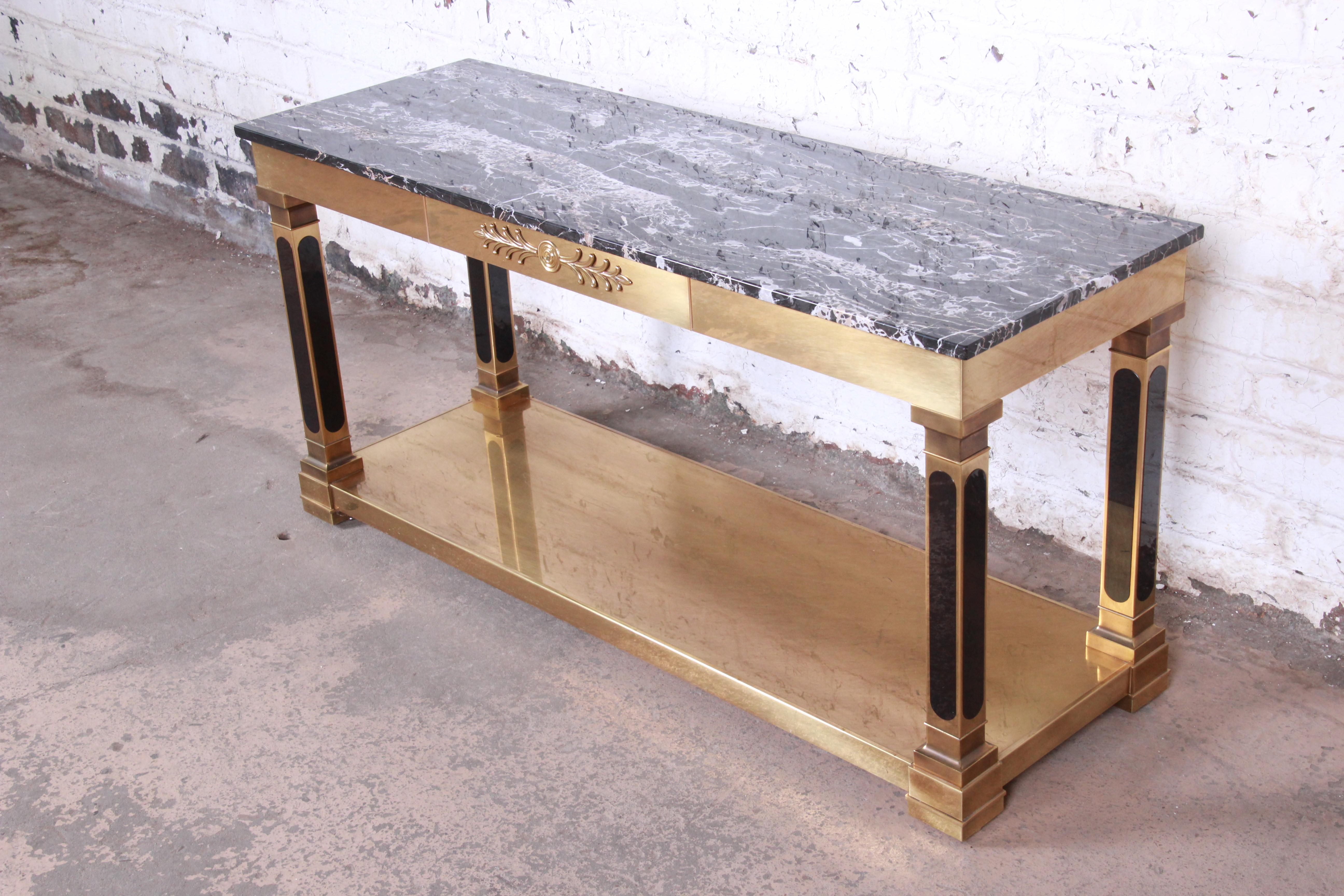 An exceptional midcentury Hollywood Regency console or sofa table by Mastercraft of Grand Rapids. The table features a stunning brass-clad frame with column legs and a beautiful marble top. It is finished on all sides and could be used in the center