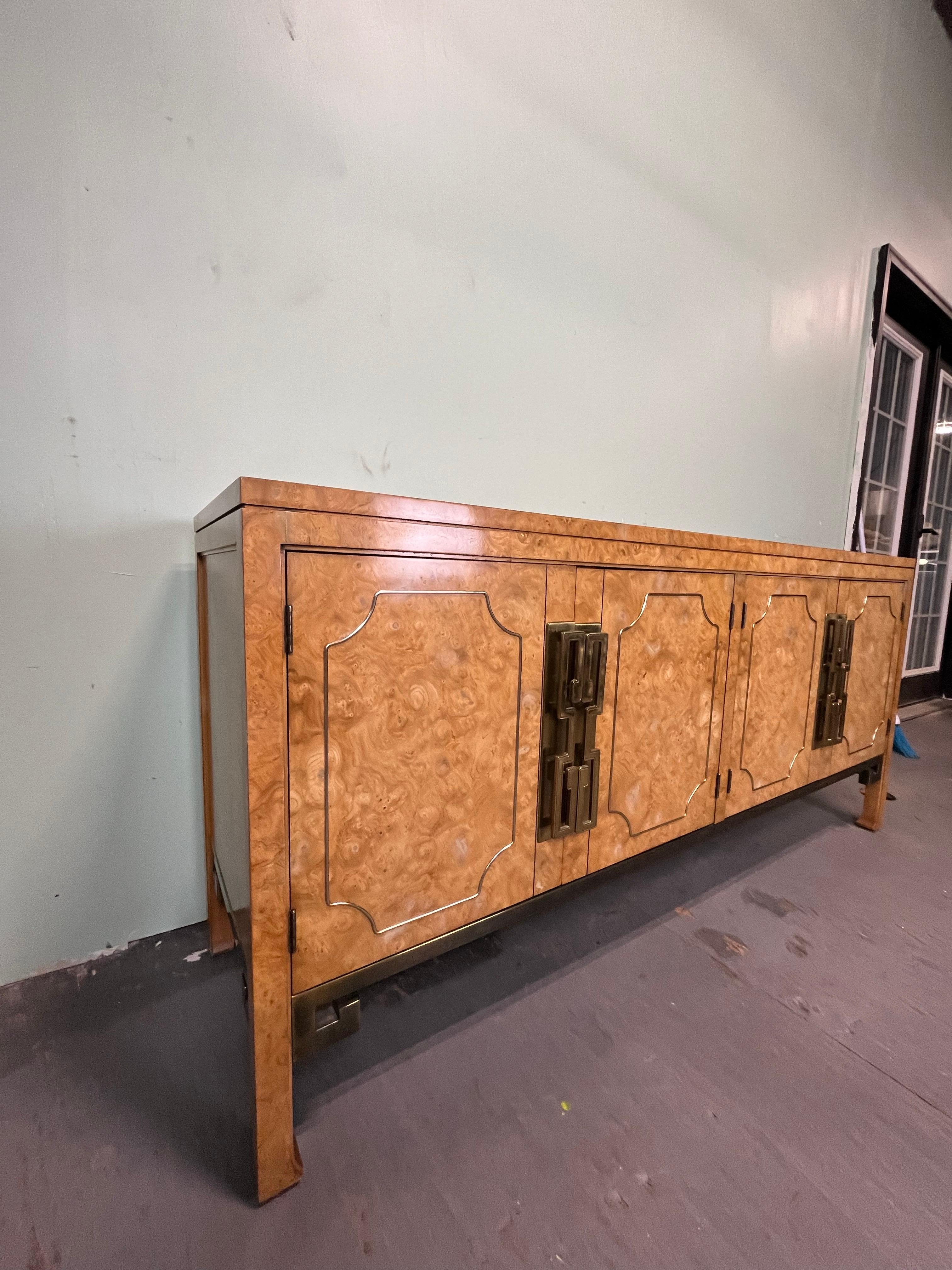 Una splendida credenza, credenza o mobile bar in stile Mid-Century Modern Hollywood Regency. Splendida venatura di radica di frassino.
Di William Doezema per Mastercraft
USA, anni '70
Legno di olmo dei Carpazi scorticato, con montature in ottone a